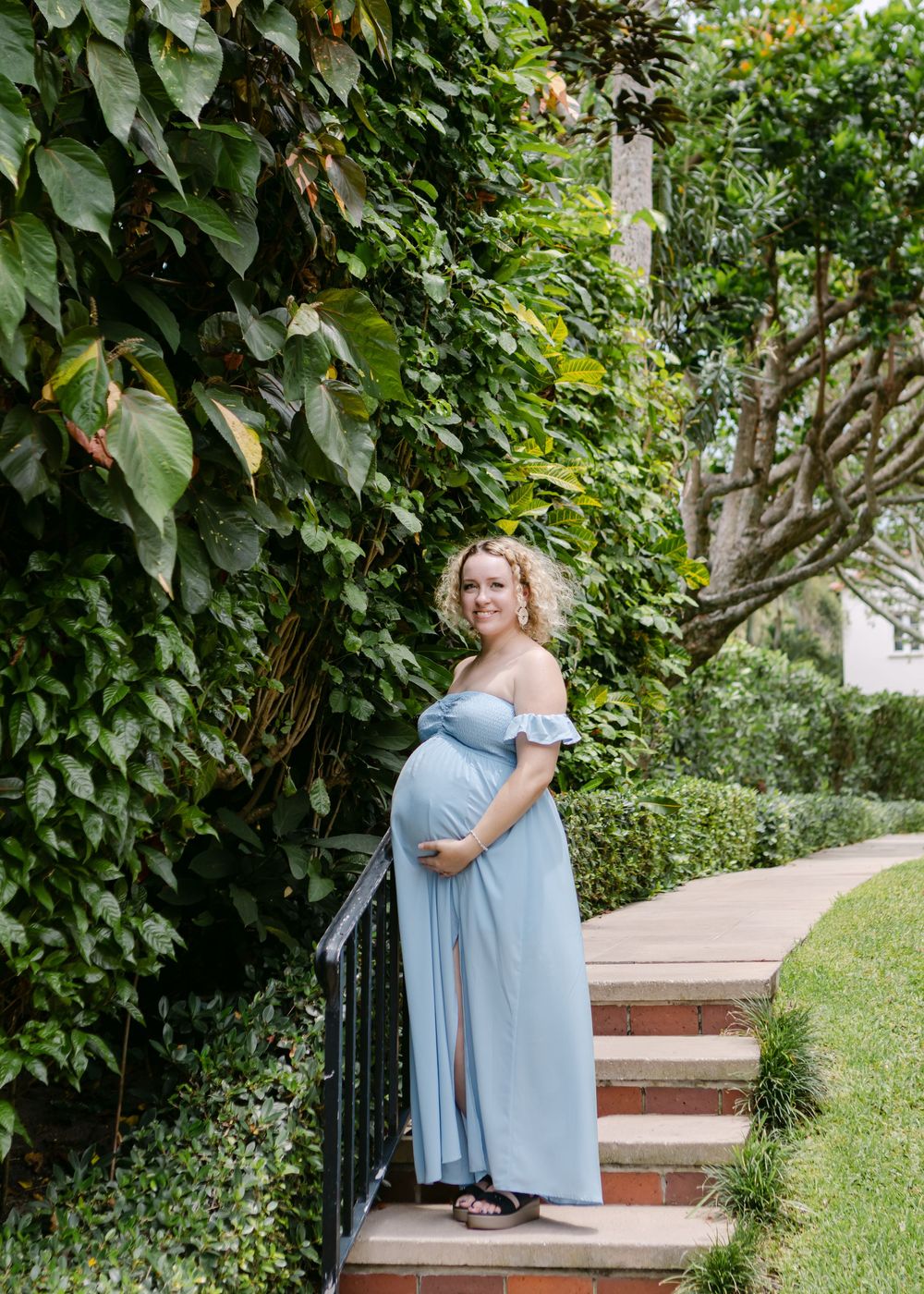 A couple shares an intimate moment among lush green foliage and garden paths.