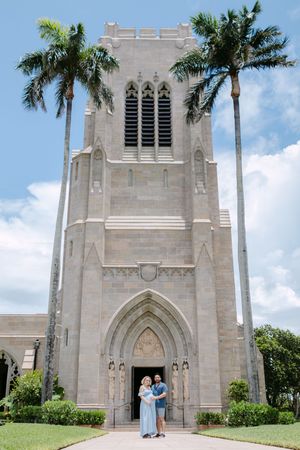Gothic church exterior with stone architecture and palm trees against a blue sky.