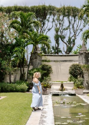 Serene garden path alongside a decorative pond with stone walls and lush greenery.