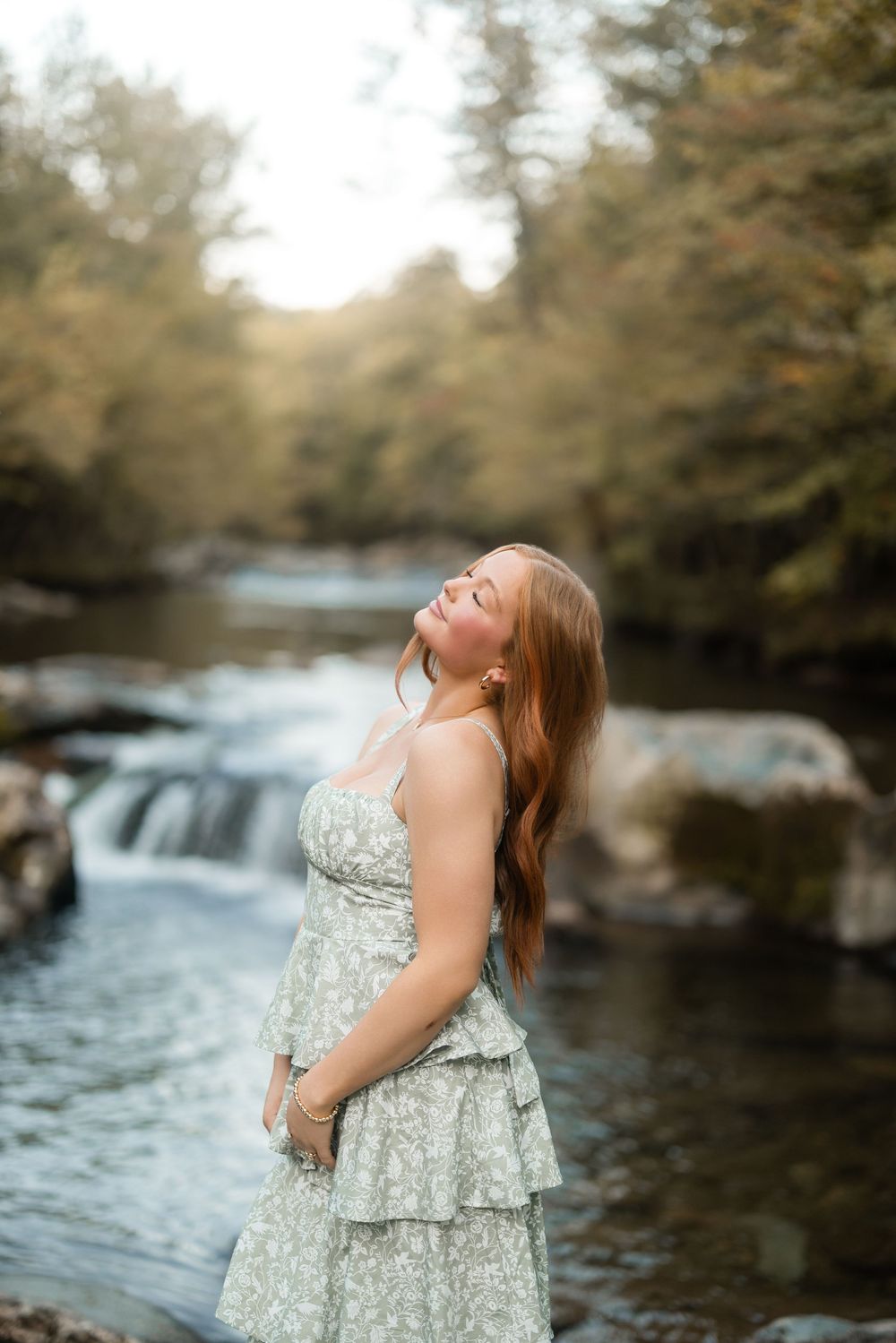 A dreamy portrait in a floral dress by a cascading waterfall in nature.