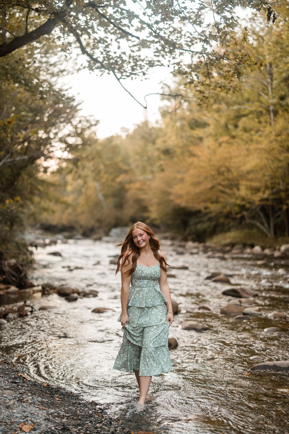A series of photos showing a person in a mint green dress twirling and playing in a scenic creek surrounded by trees.