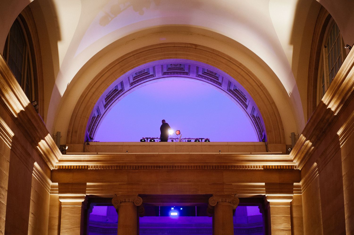Elegant ballroom with arched ceilings and dramatic purple lighting creates an upscale ambiance.