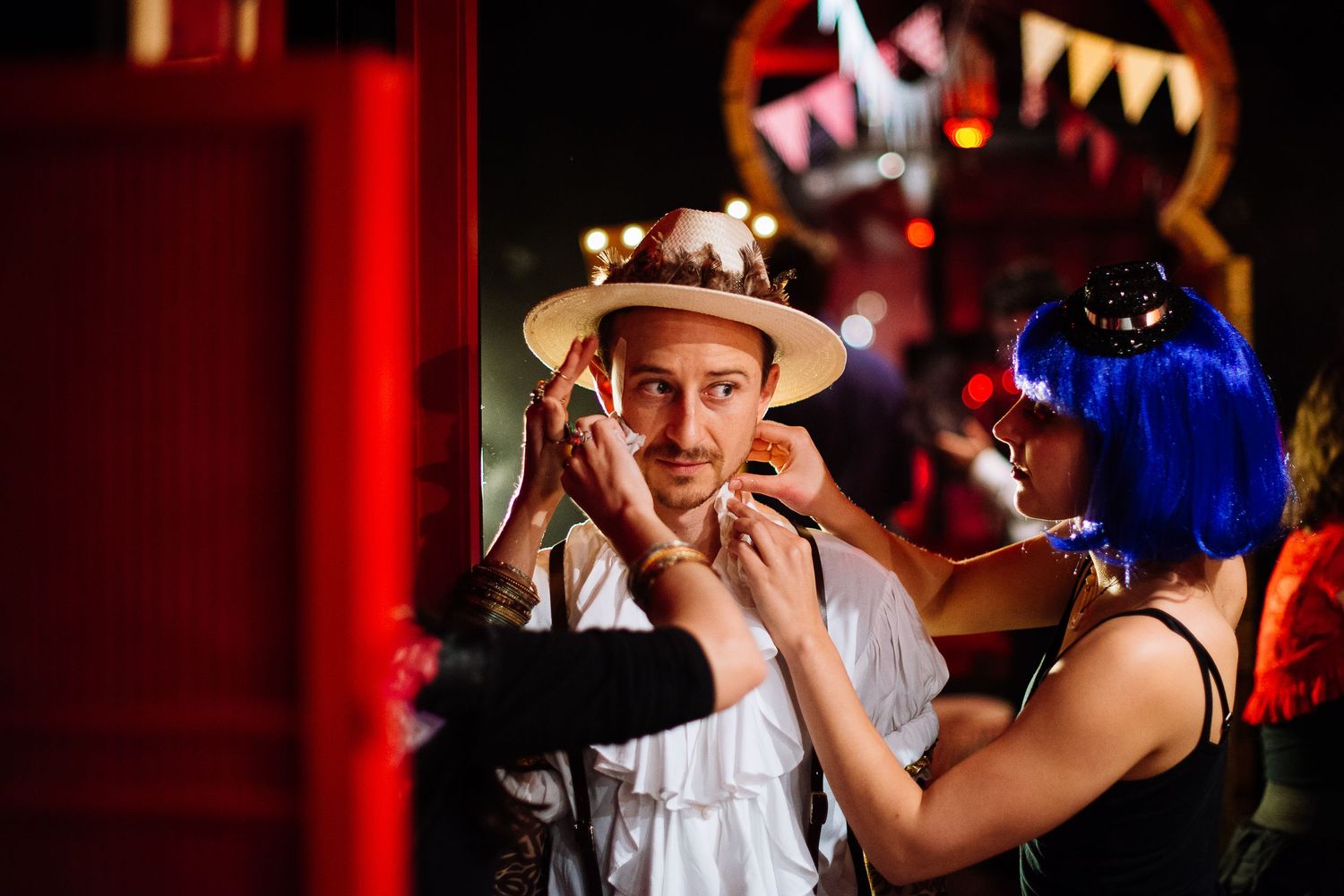 People dancing and celebrating at a festive party with red ambient lighting.