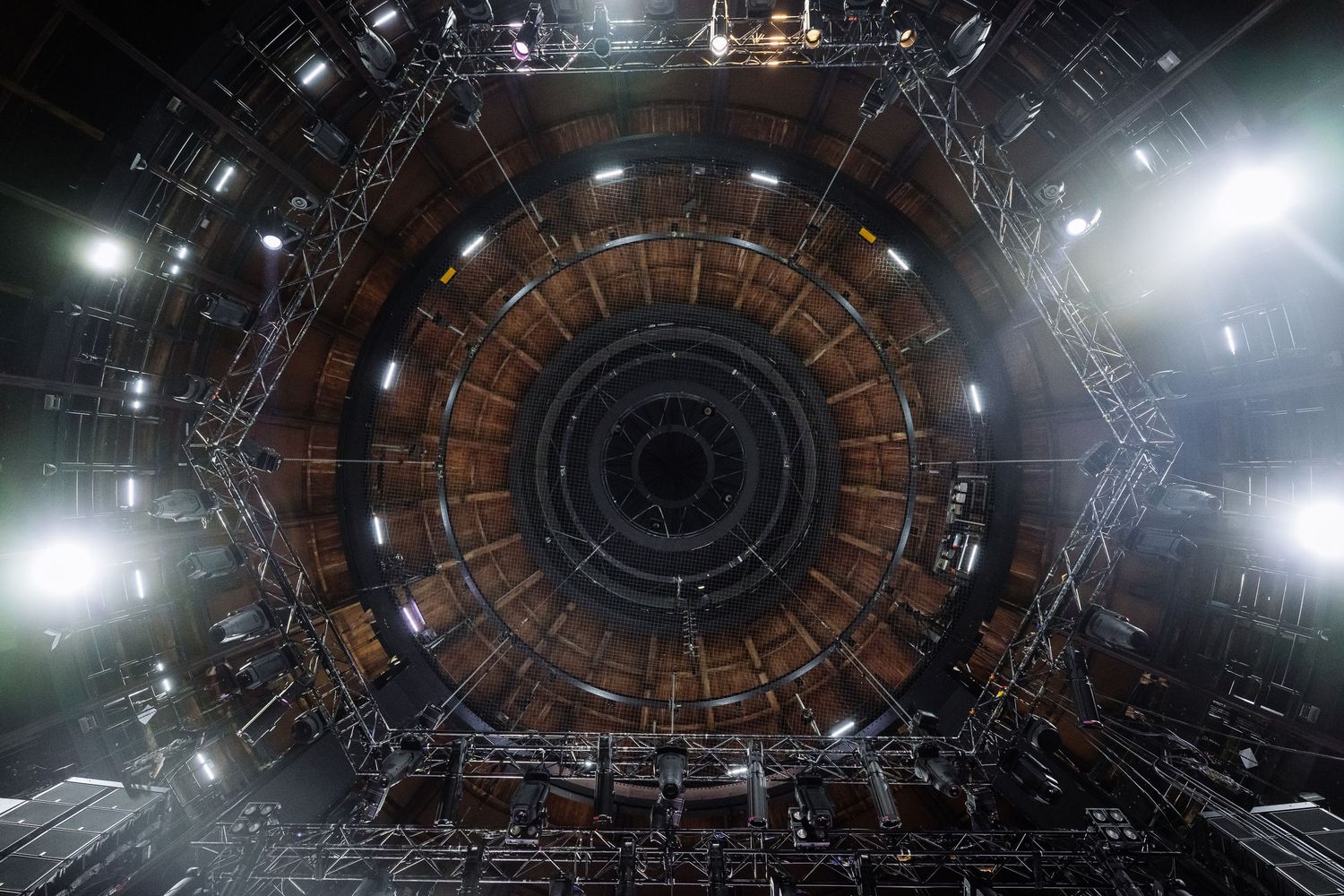 Circular ceiling view of stage lighting and technical equipment in a theater.