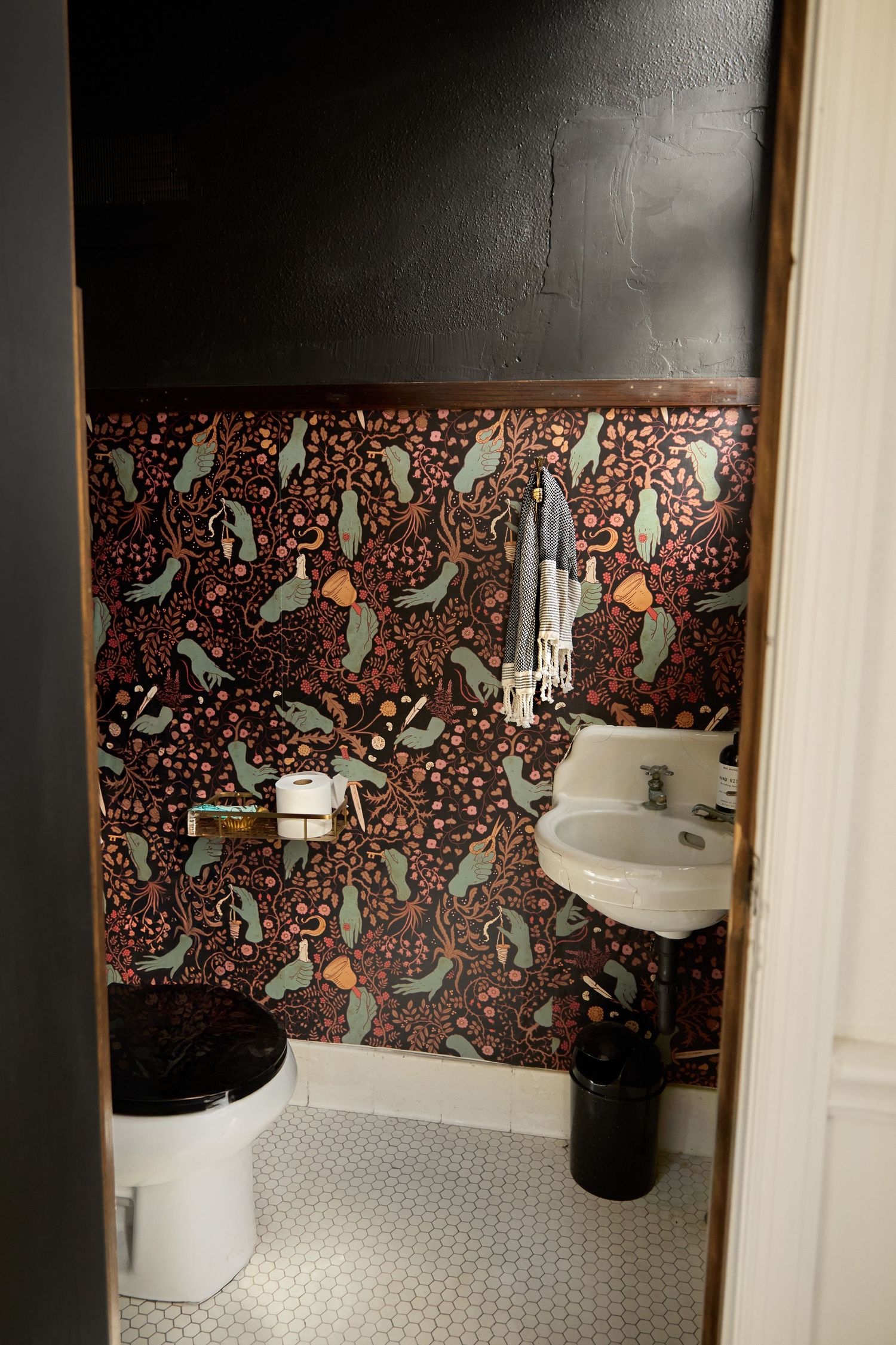 Vintage bathroom interior featuring bold floral wallpaper pattern and white hexagonal floor tiles.