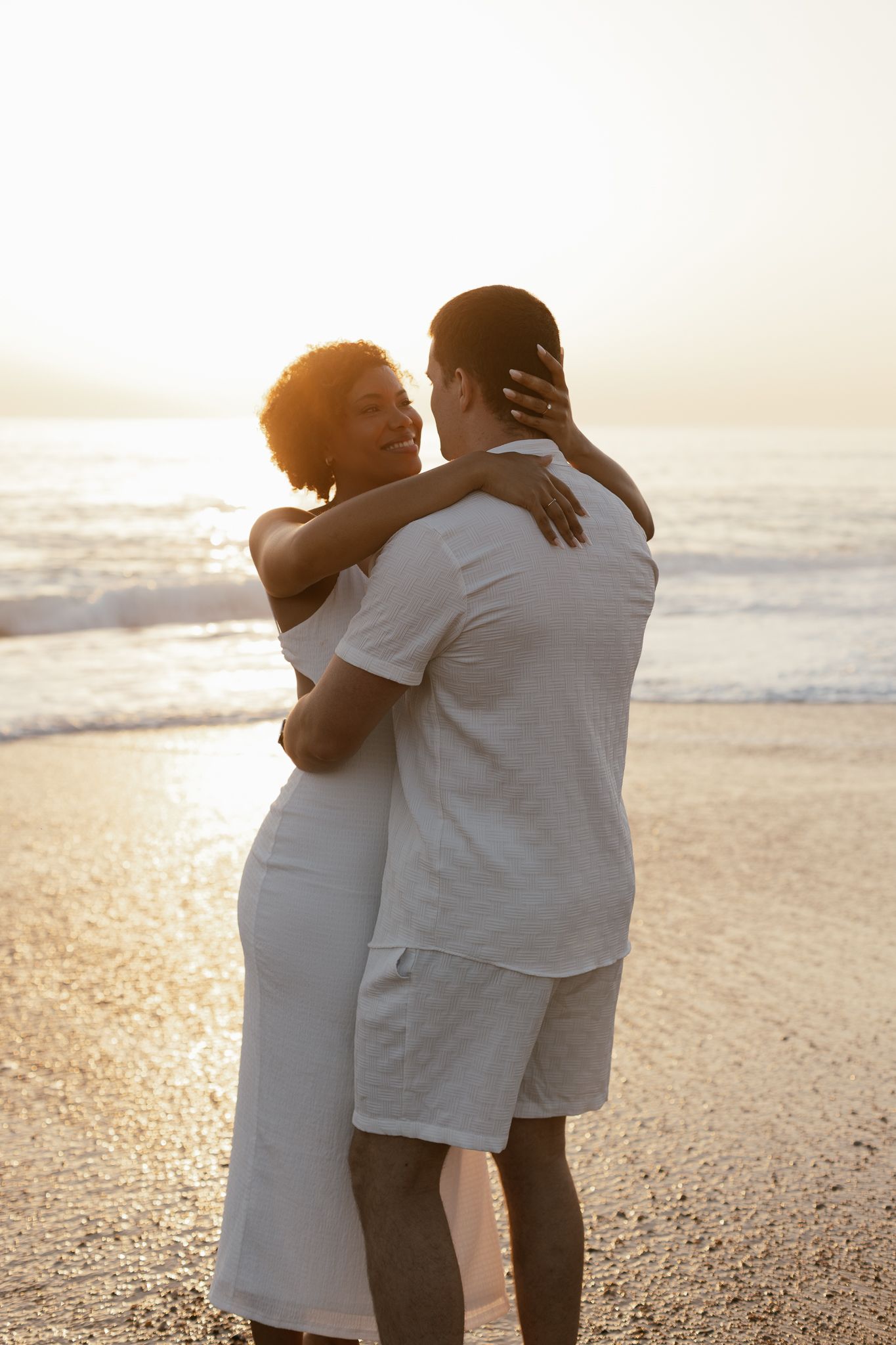 Photographie de couple complice sur la plage vendéenne, capturée en fin de journée avec une lumière douce et naturelle.
