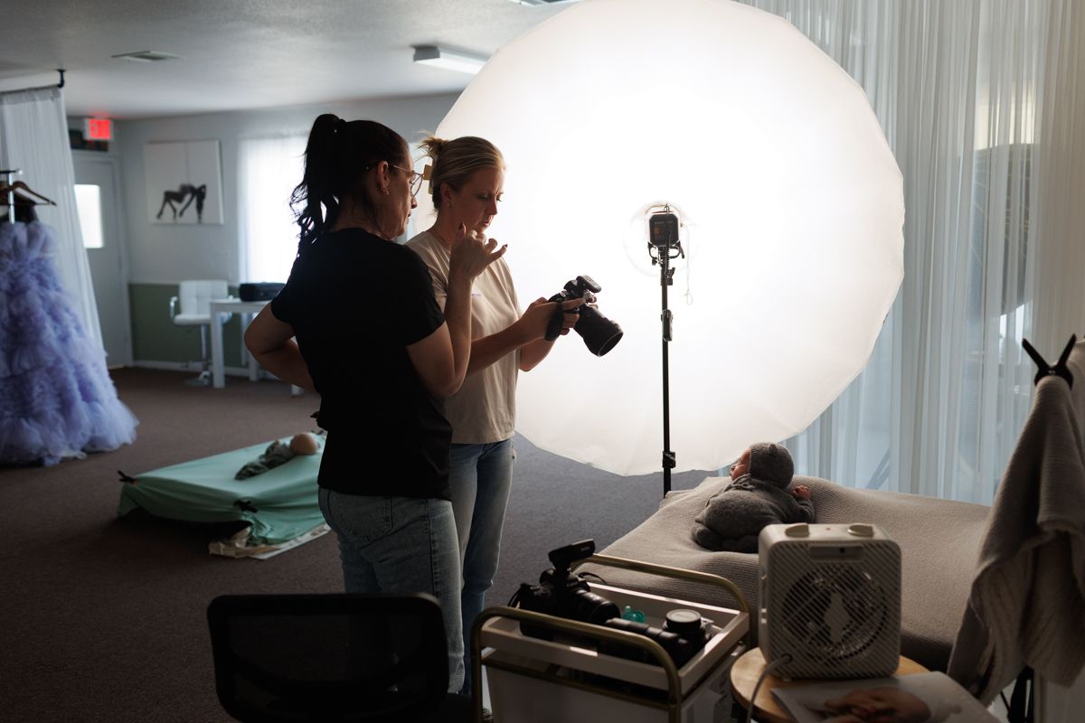 Behind the scenes photo shoot setup with large white backdrop and lighting equipment.