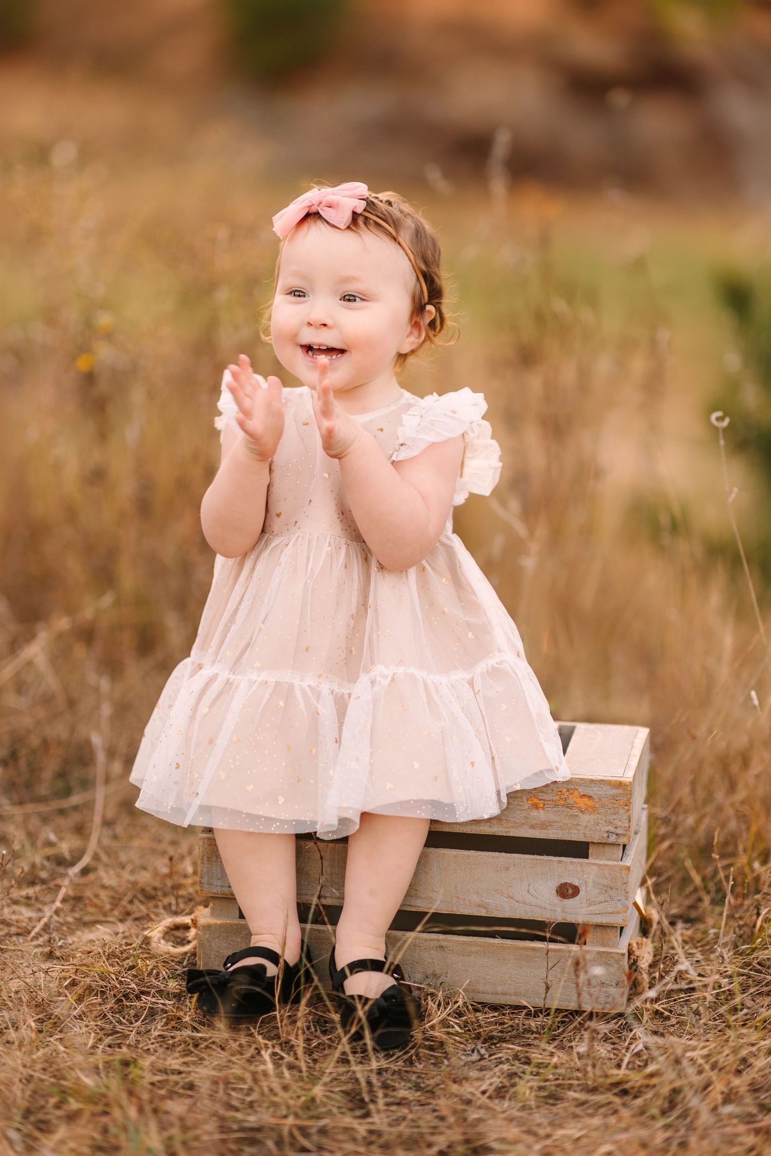 Three photos of a small child in a white dress sitting on a wooden bench in a rustic outdoor setting.