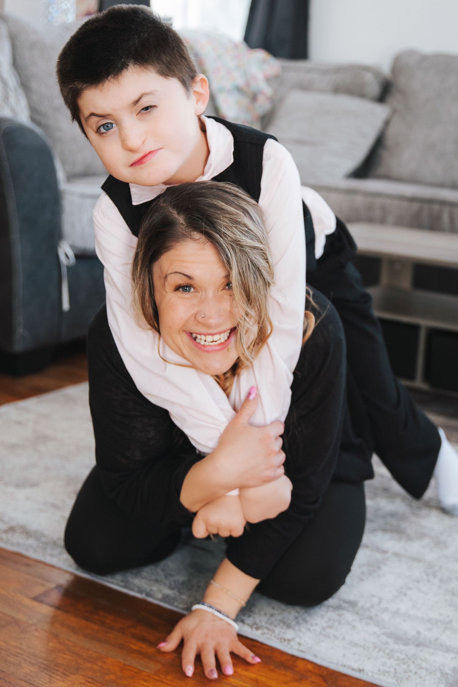 Playful indoor family photoshoot with joyful expressions on a light gray carpet.