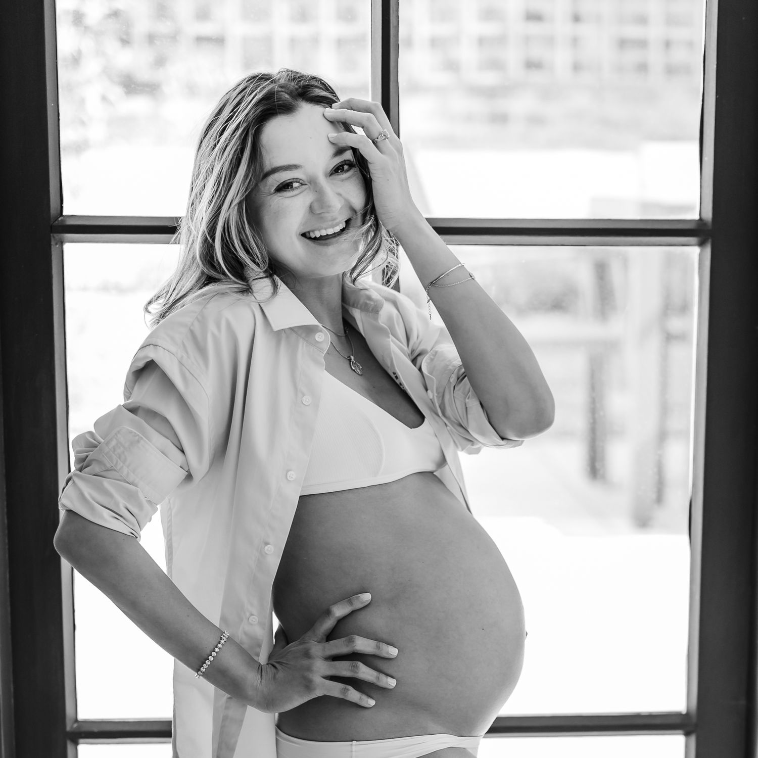 Window-lit maternity portraits in black and white with natural expressions.