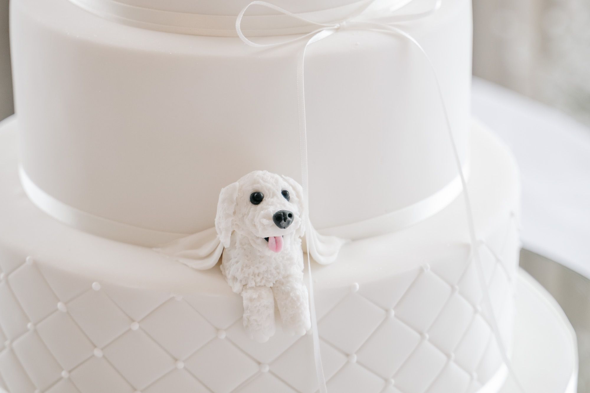 White wedding cake decorated with delicate quilted pattern and small ornamental details.