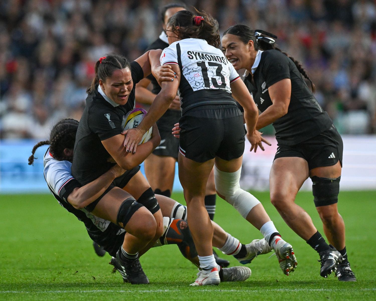 Rugby players crouch in a scrum formation during a match on a grass field.