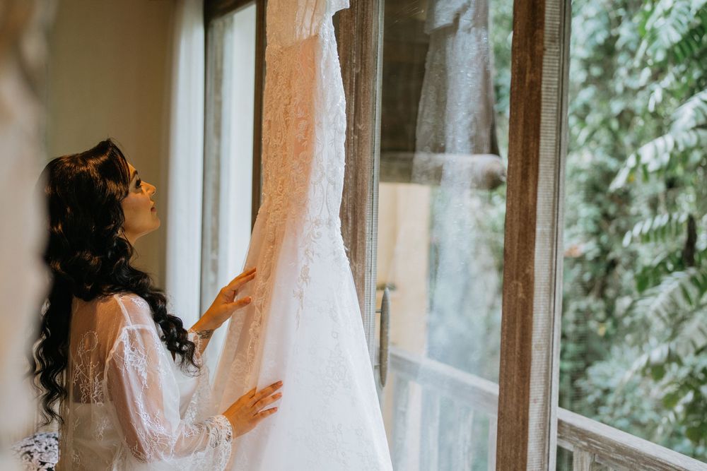 Bridal preparations by window with natural light streaming through sheer curtains.