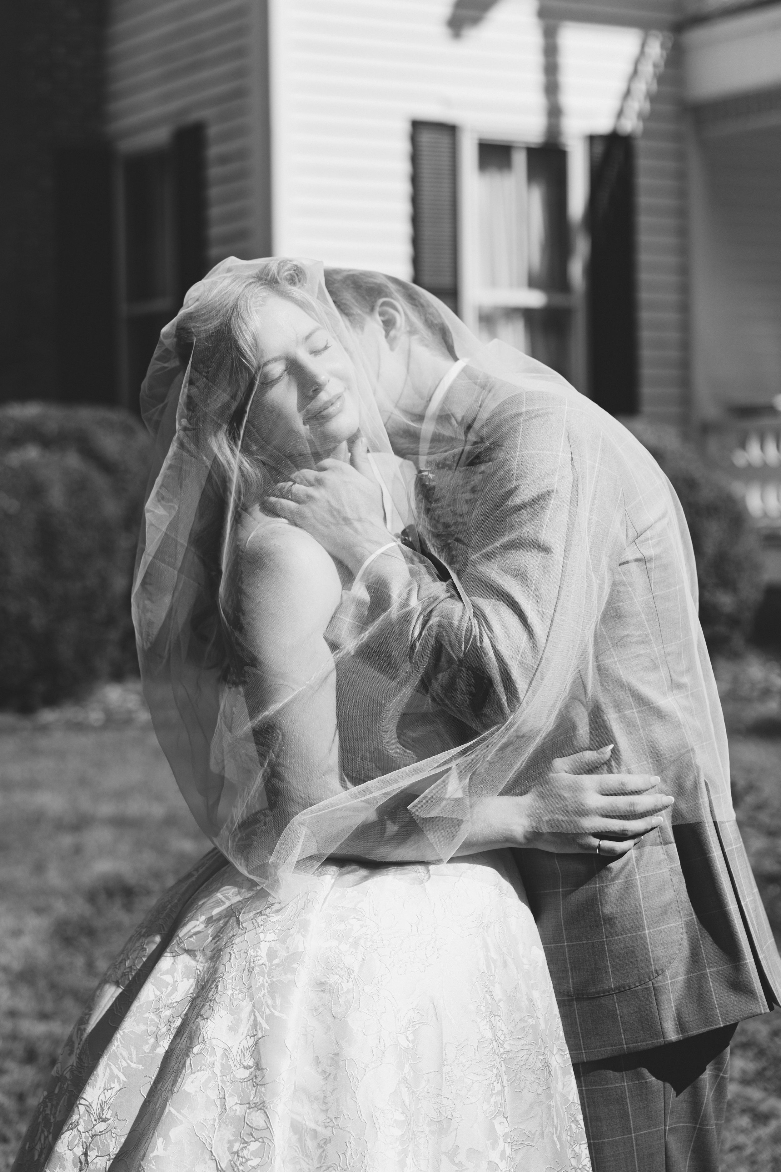 romantic black and white photo sequence shows a couple in wedding attire sharing an intimate moment under a veil. wedding photographer