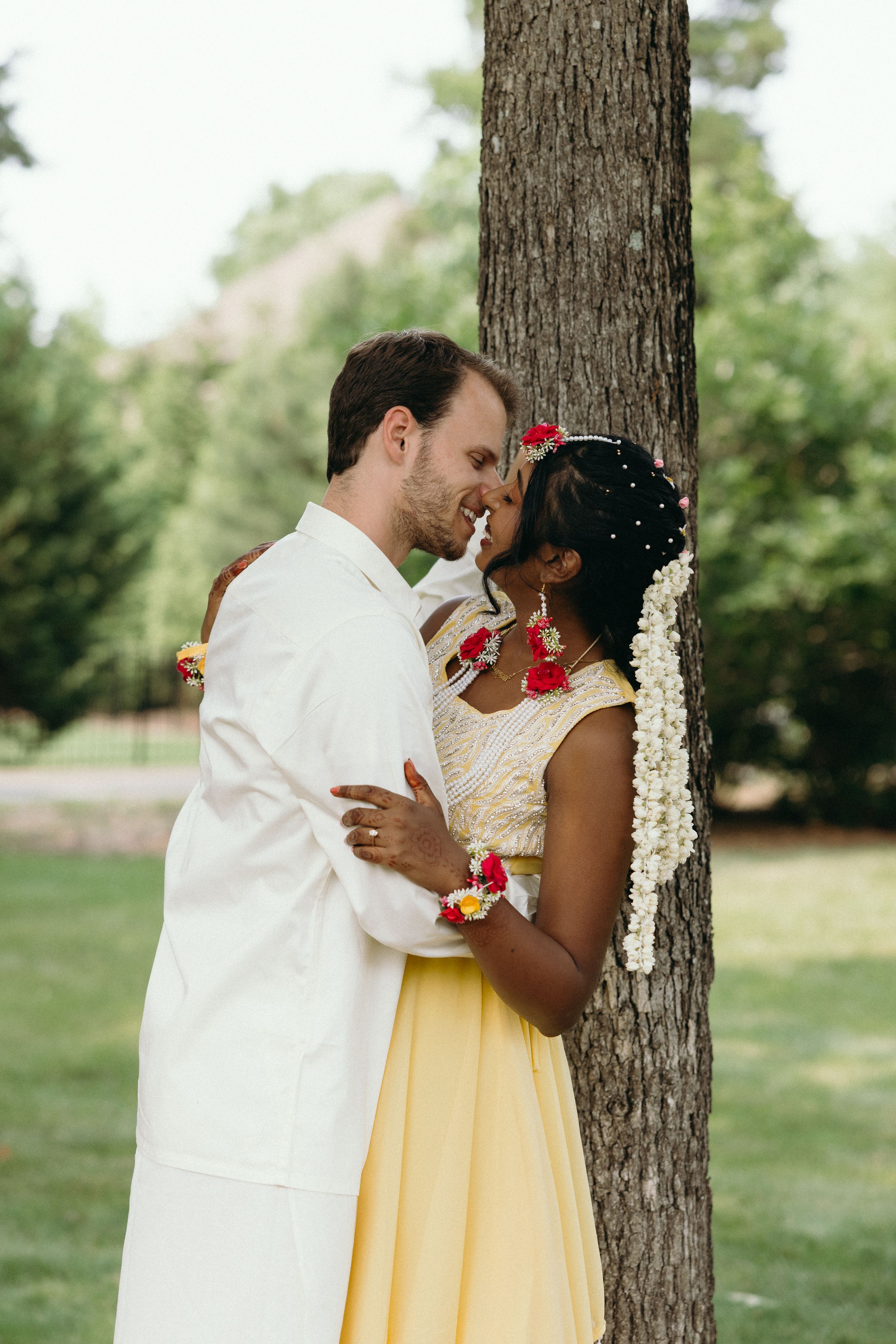 Romantic wedding moment captured under a large tree in a garden setting. Luxury Estate Wedding Photographer in NC