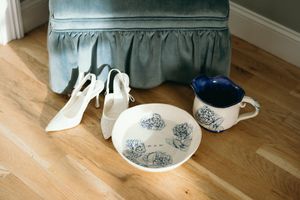 Wedding dress train flows elegantly across hardwood floor near blue and white ceramic vases. Luxury Estate Wedding Photographer in NC