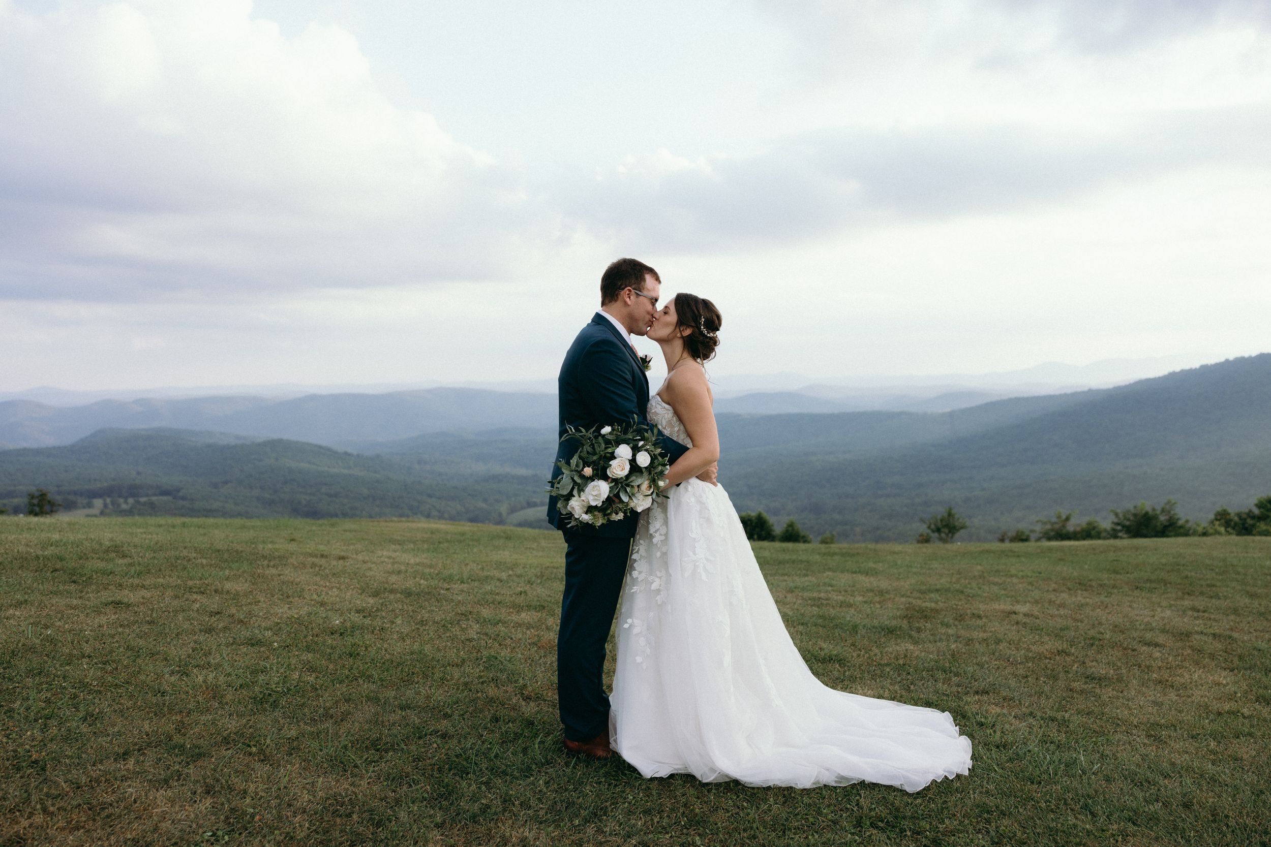 Scenic mountain landscape provides stunning backdrop for wedding portraits on rolling hills. Luxury Estate Wedding Photographer in NC