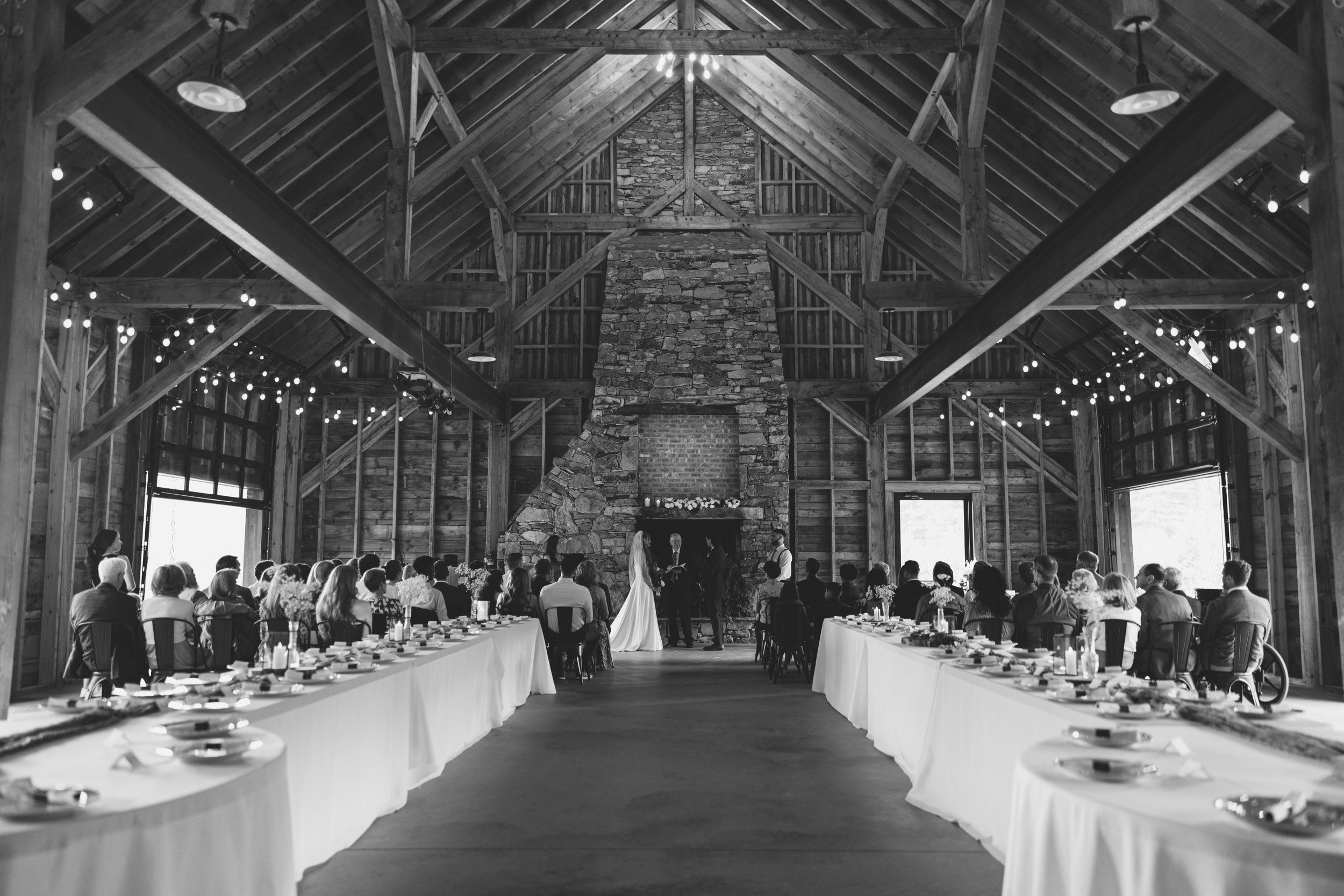 Interior view of a rustic barn wedding venue with elegant table settings and string lights. Luxury Estate Wedding Photographer in NC