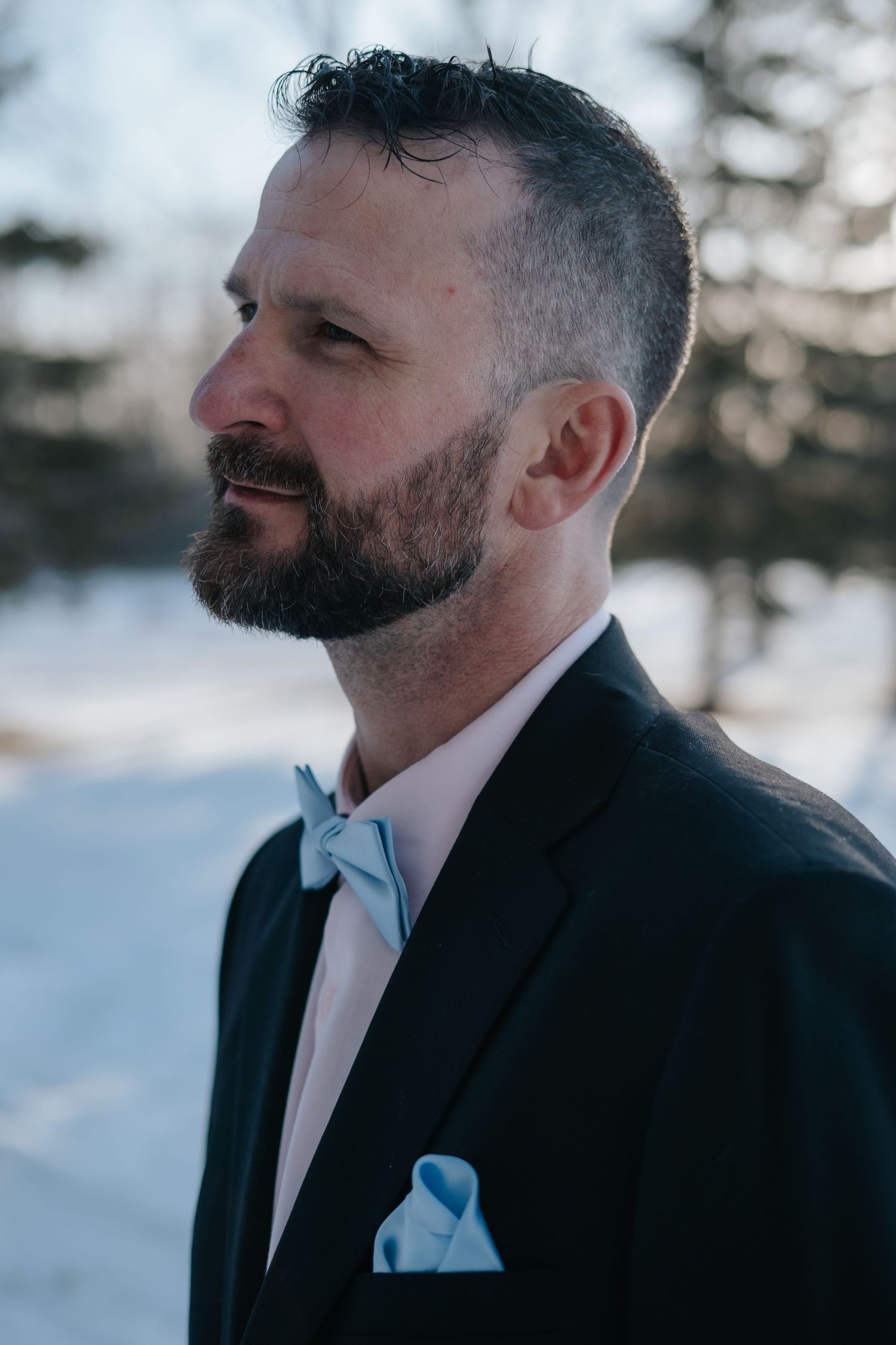 Winter portrait of a groom in a black suit and light blue bowtie.