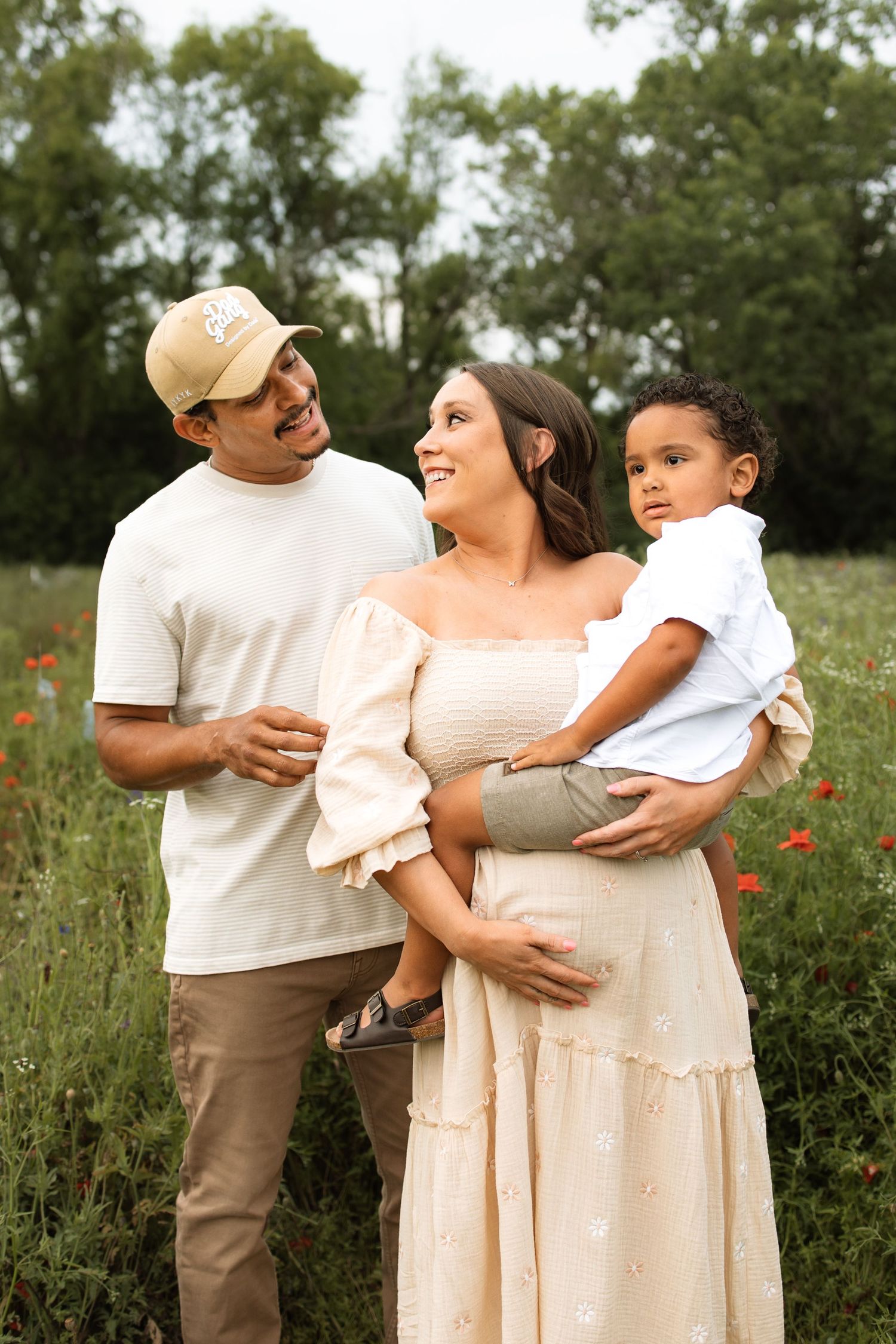 Family enjoying time together outdoors in a meadow wearing light neutral colored clothing on a summer day.