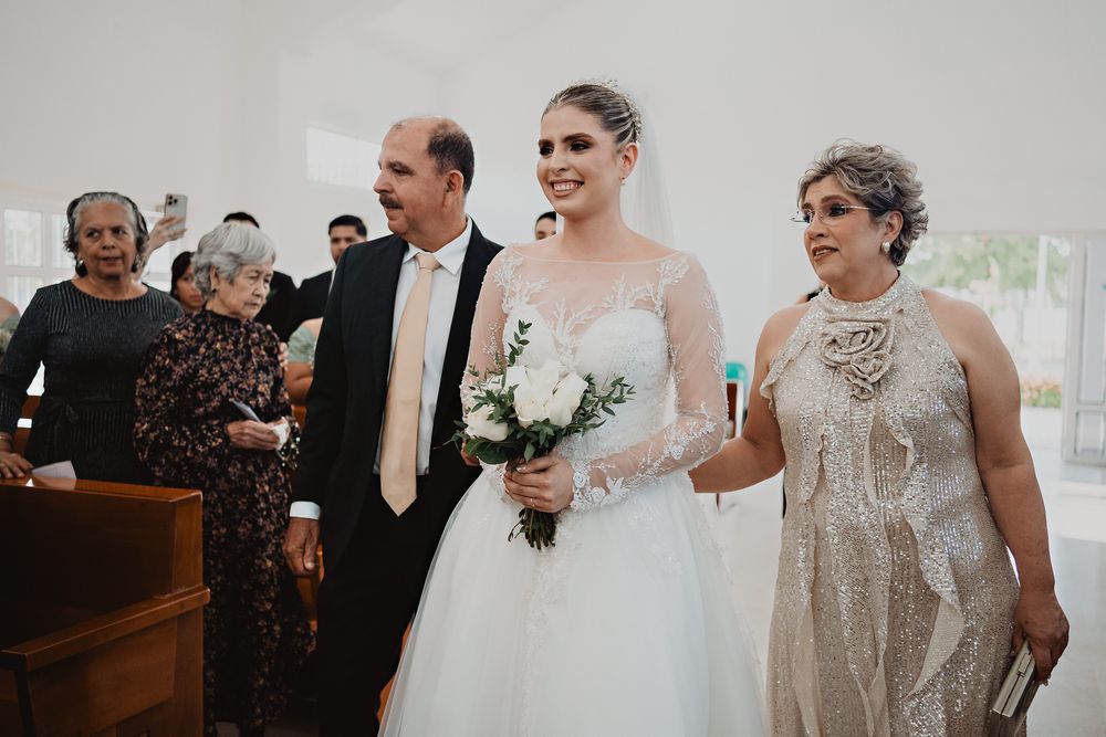 A wedding party walks down the church aisle after the ceremony with the bride wearing a traditional white gown and veil.