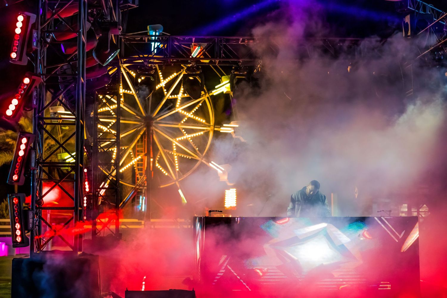 Concert stage with vibrant yellow lighting effects and fog creating dramatic atmosphere during a live performance.