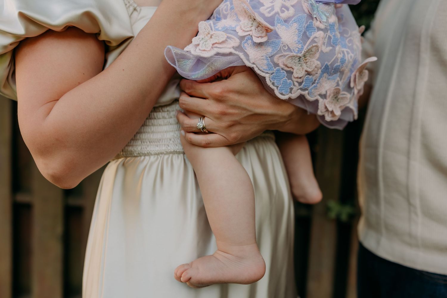 Close-up of someone holding a baby wearing a light blue ruffled dress and tiny bare feet.