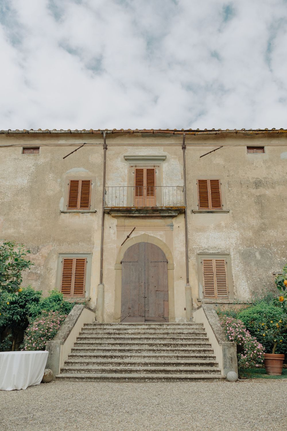 Classical Tuscan villa entrance with grand staircase and shuttered windows.