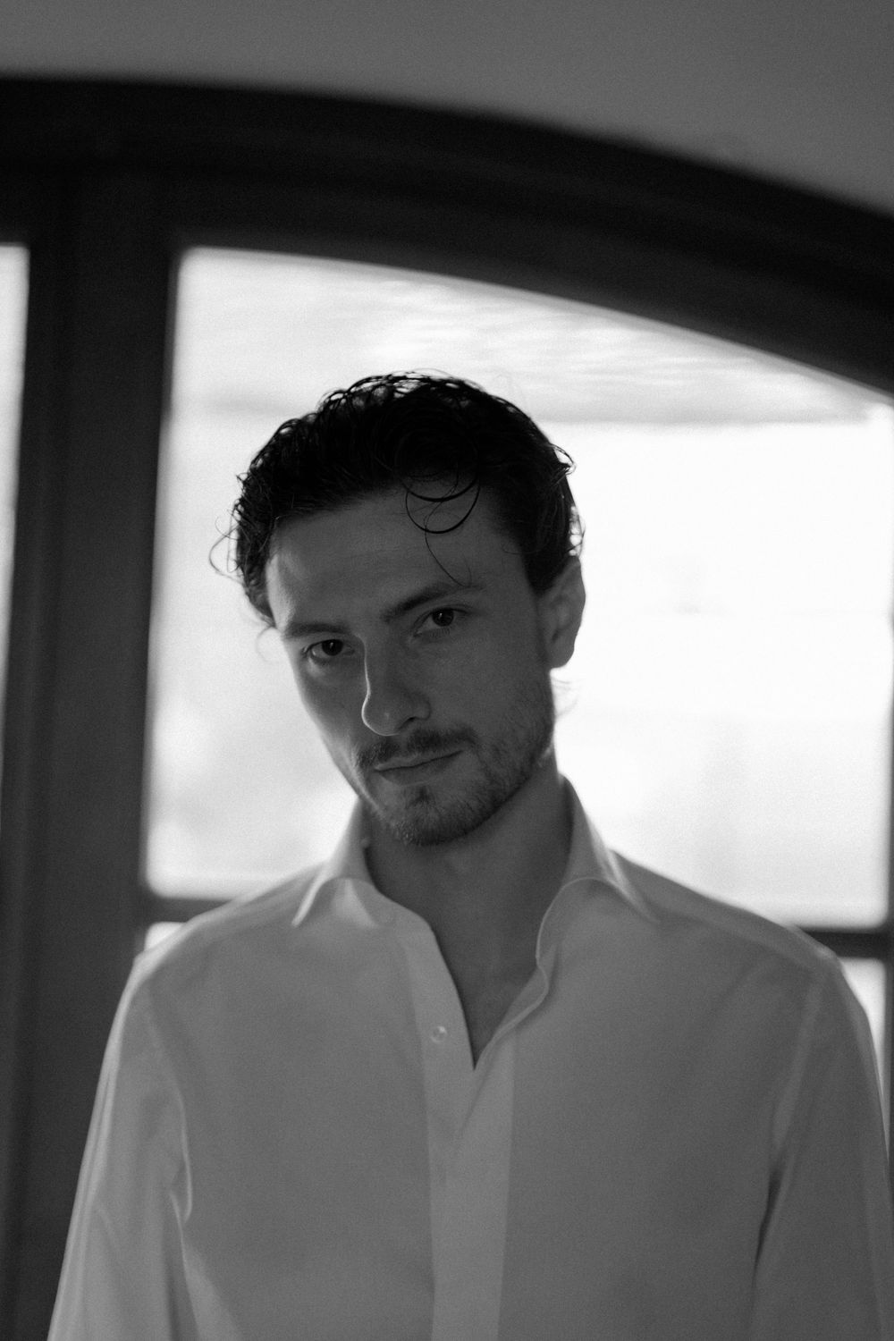 Portrait of a man in white dress shirt captured in dramatic black and white lighting.