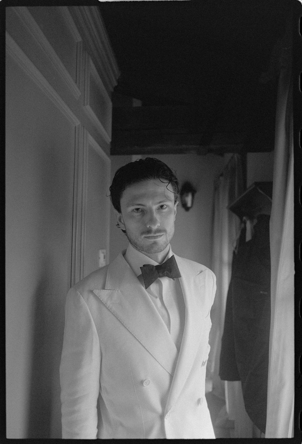 Classic black and white portrait of a man in white tuxedo and bowtie.