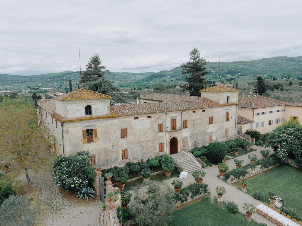 Rustic Italian villa nestled in rolling hills with cypress trees and manicured gardens.
