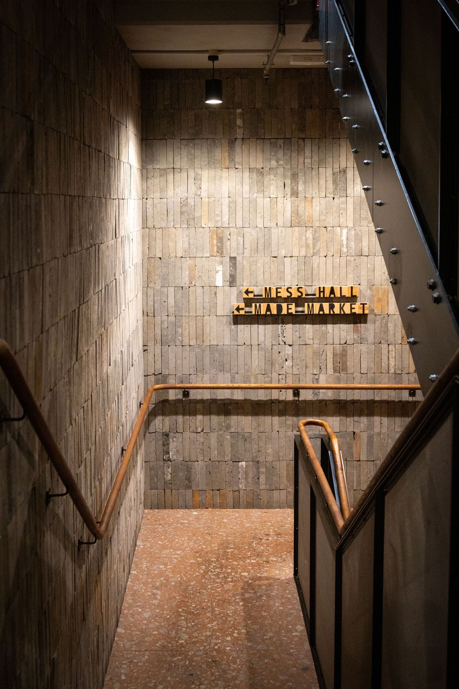 Warm-toned stairwell with timber walls and 'Mess Hall' sign at the end.