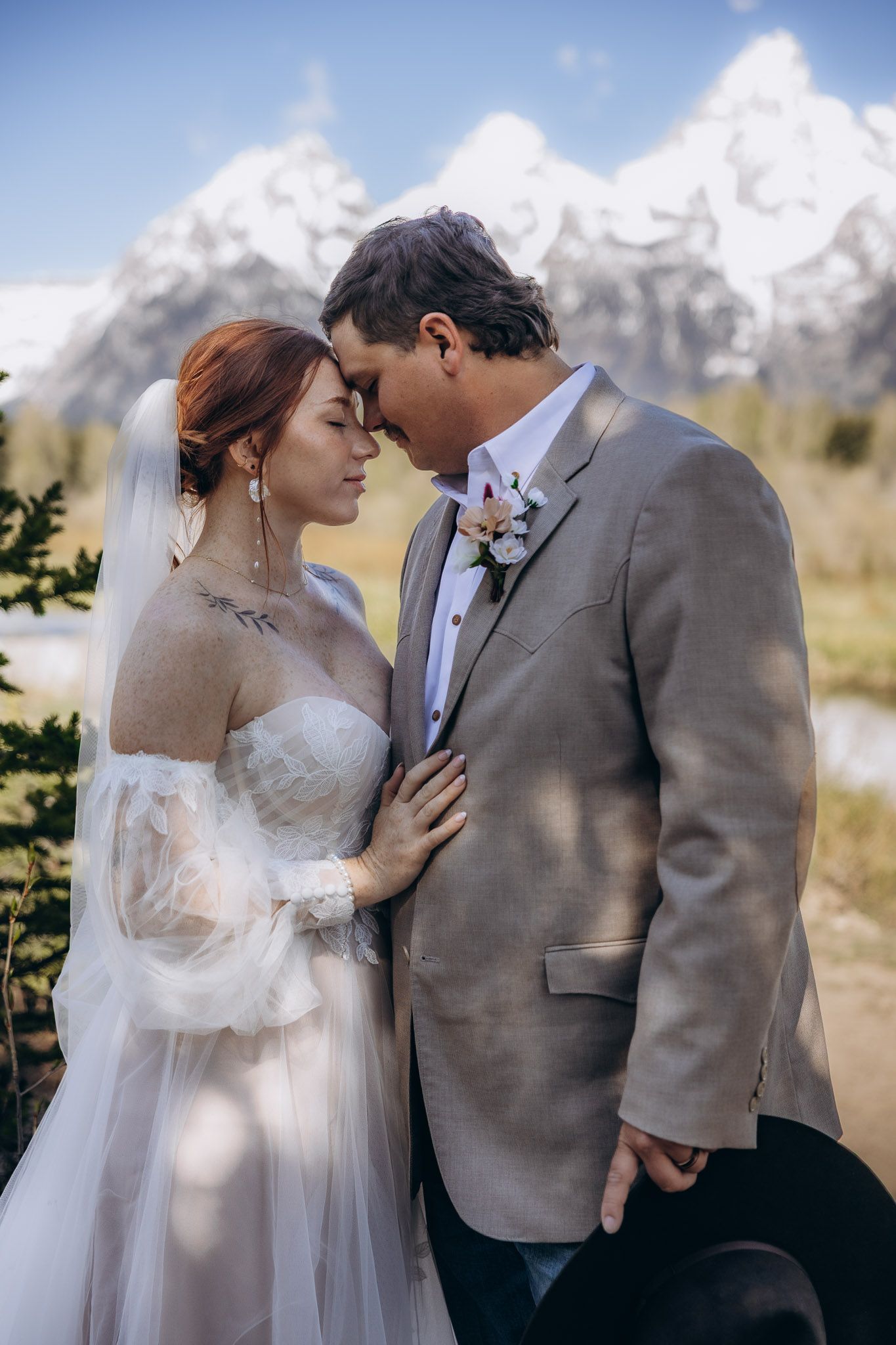 A romantic wedding portrait set against majestic snow-capped mountains in a scenic outdoor setting.
