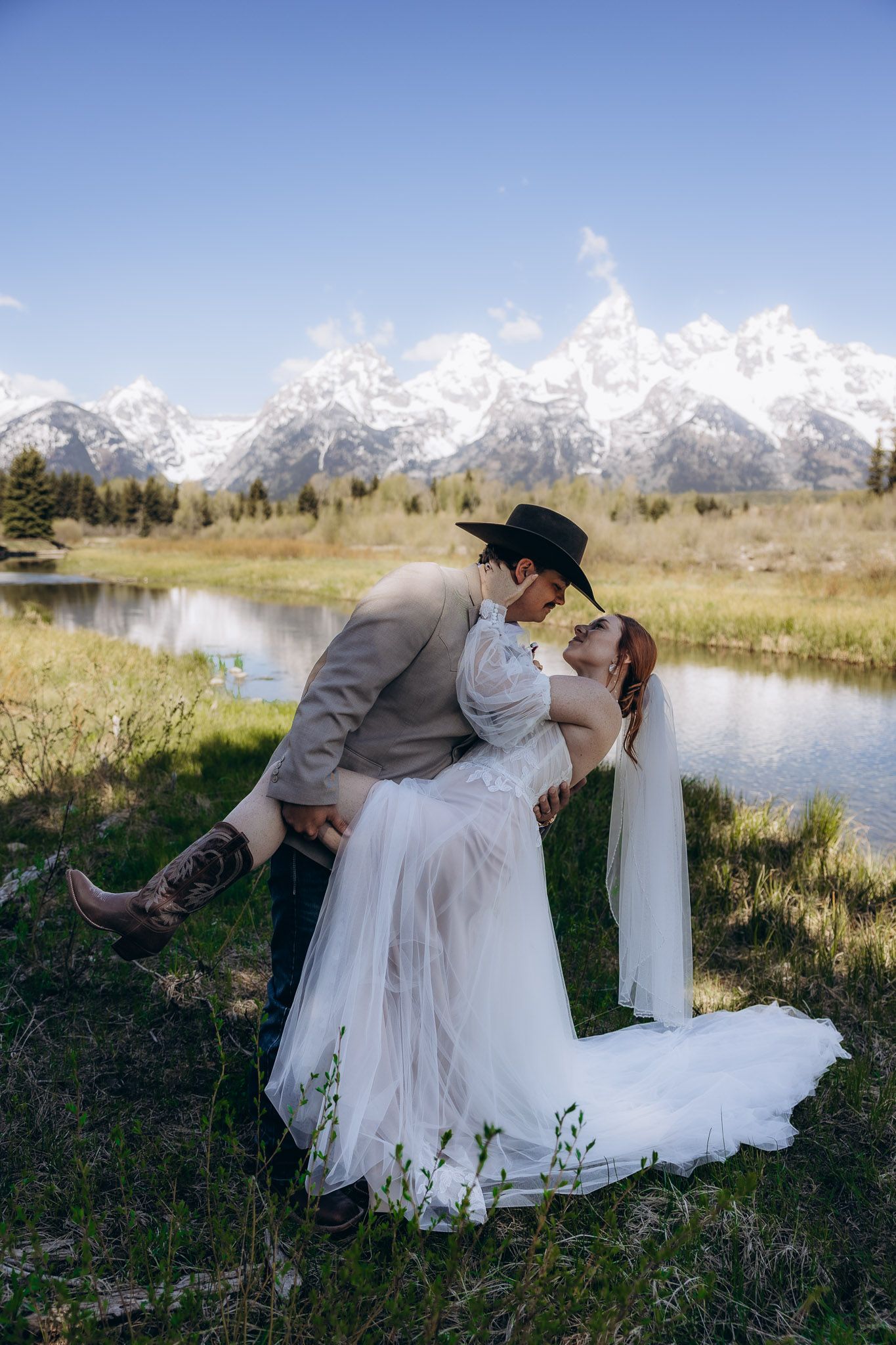 Romantic wedding photo with couple dancing by mountain stream in Grand Tetons National Park.