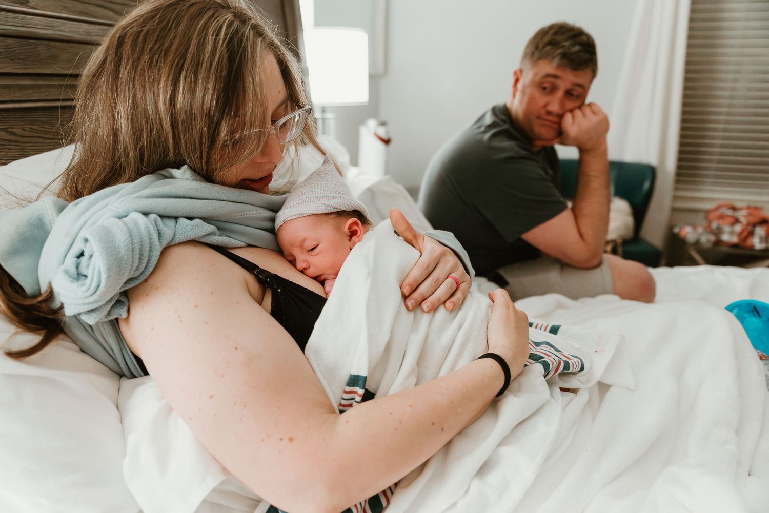 A family shares an emotional moment on a hospital bed after the arrival of a newborn baby.