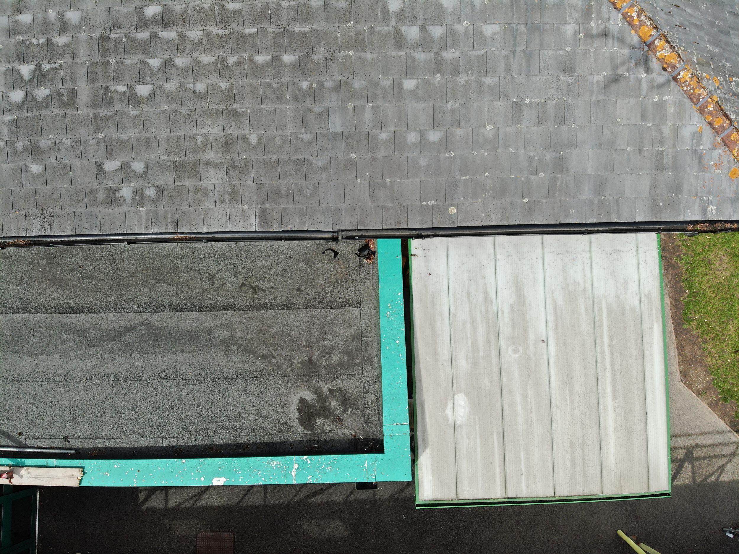 Top-down view of a gray rooftop surface with turquoise trim and contrasting white panels.