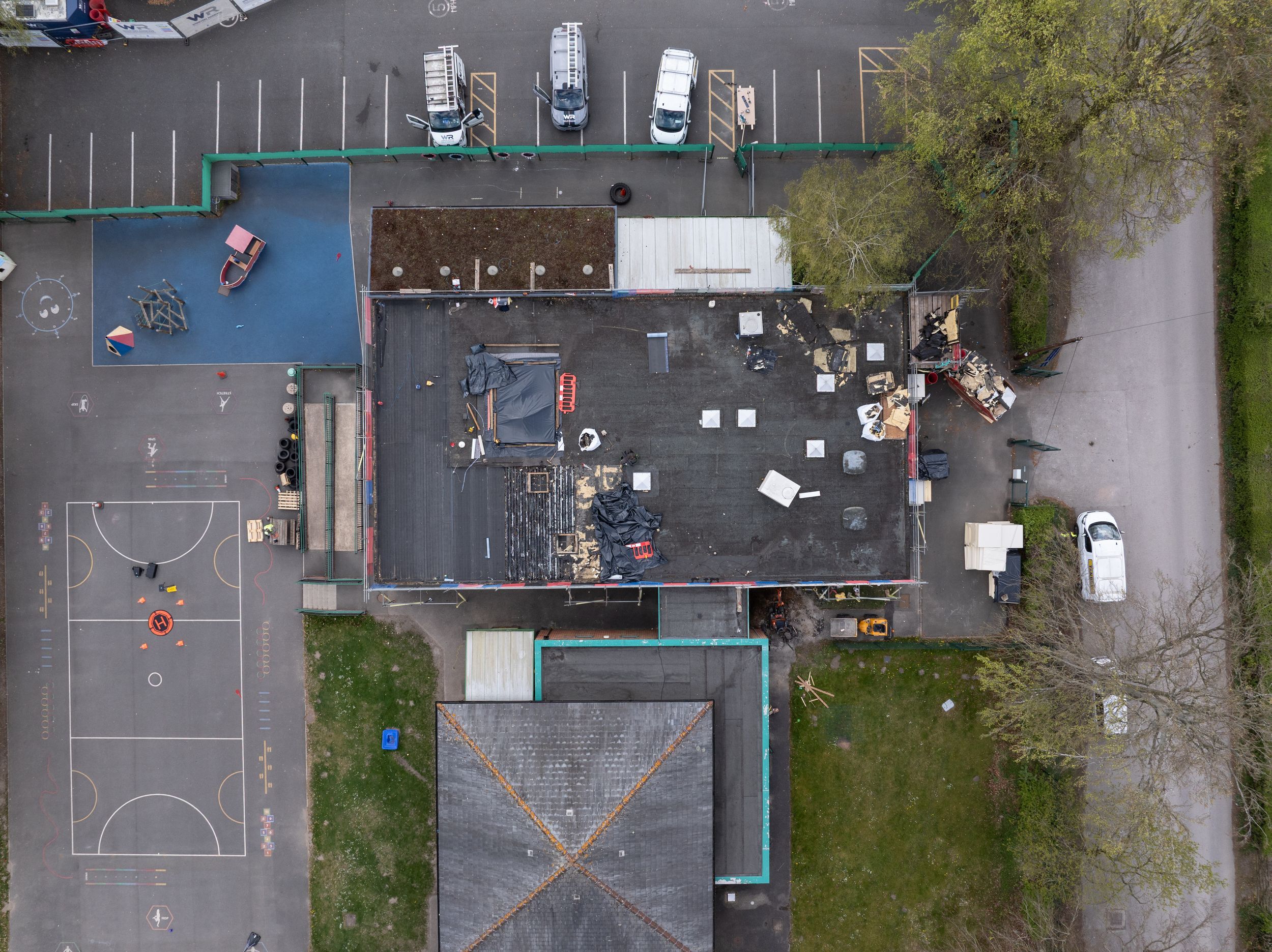 Bird's eye view of a building complex with basketball courts and parking areas.