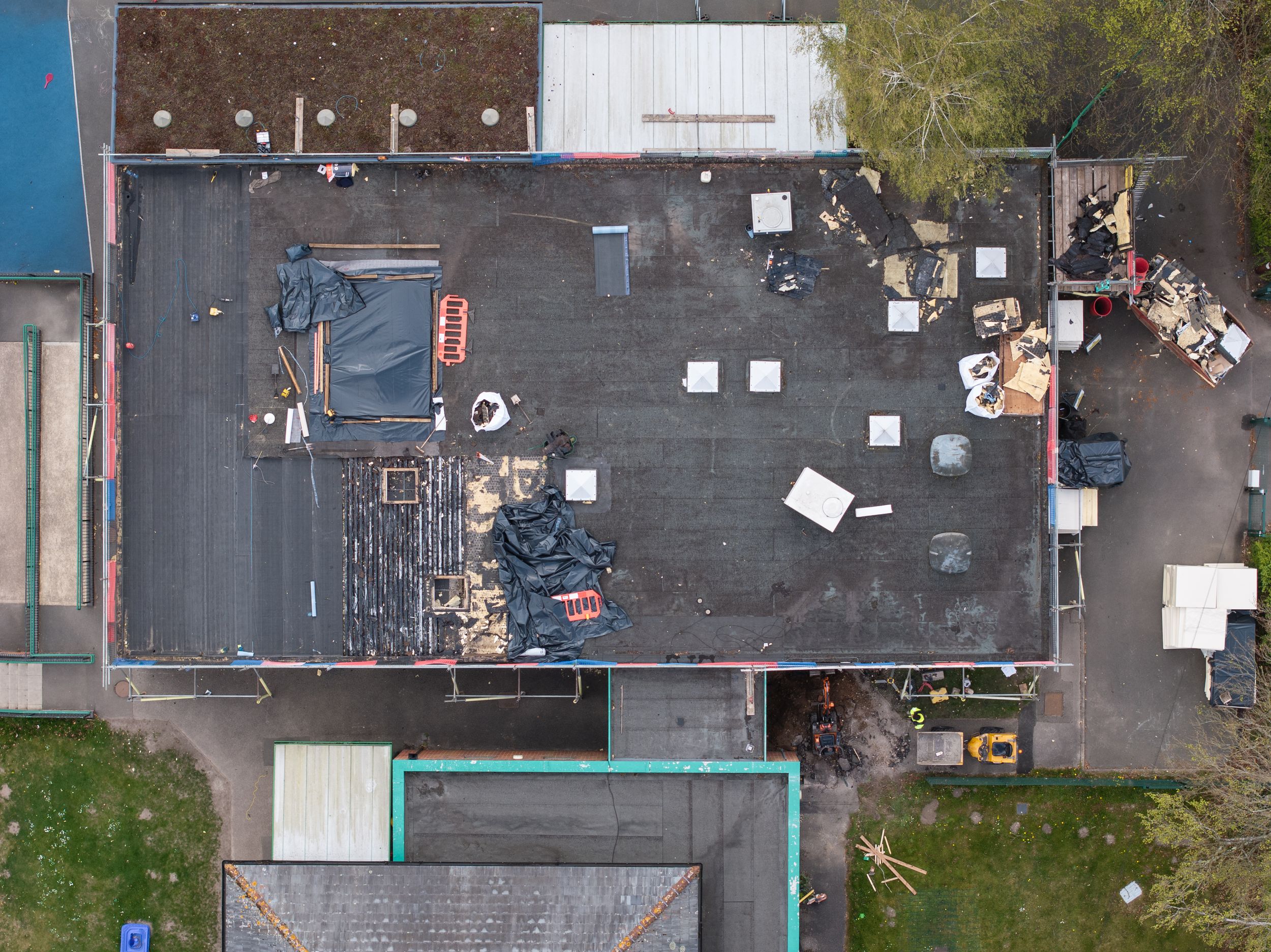 Aerial view of a flat commercial roof with scattered debris and equipment on a black surface.