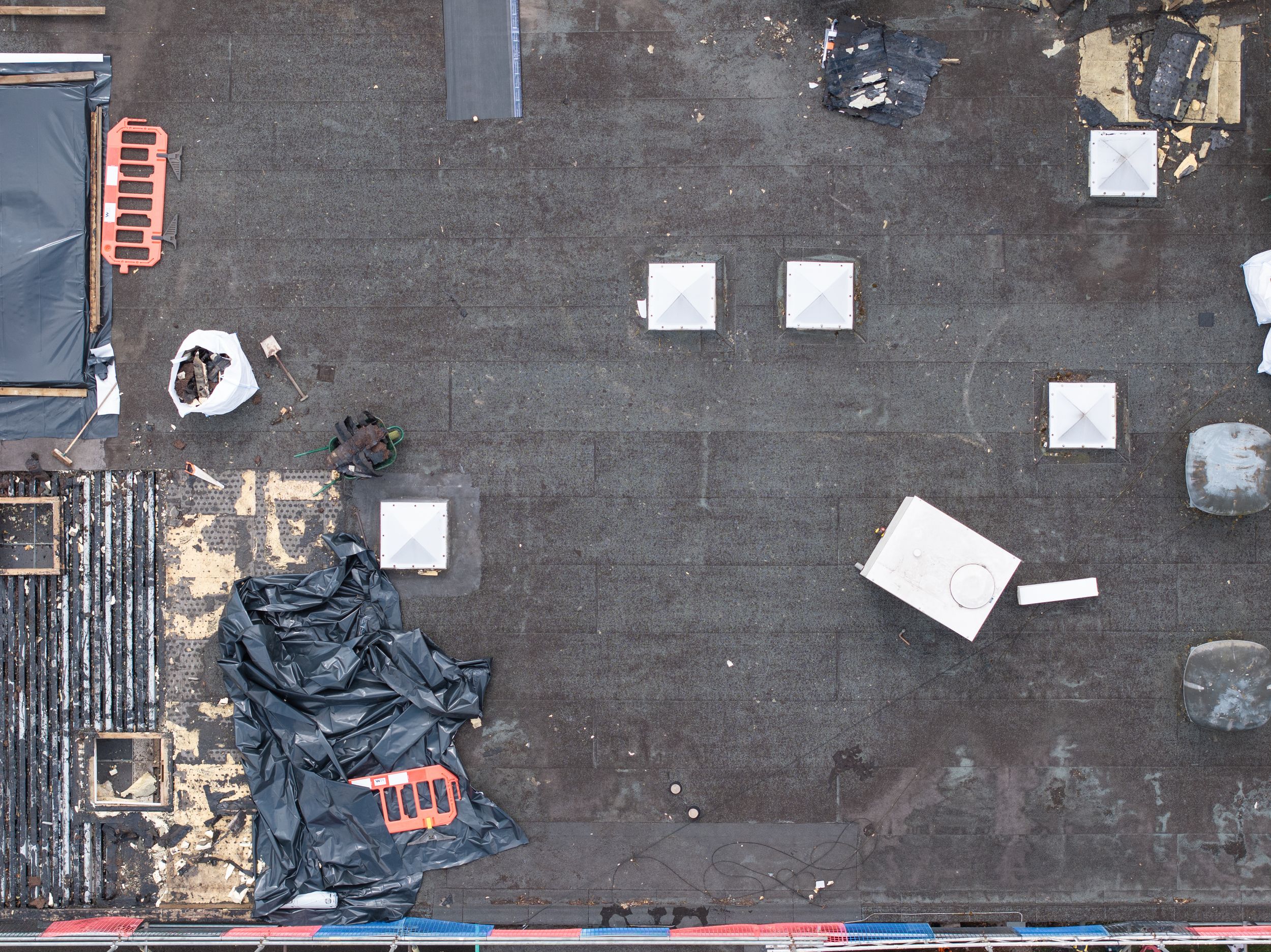 Aerial view of a dark rooftop with scattered white squares and debris against a black surface.