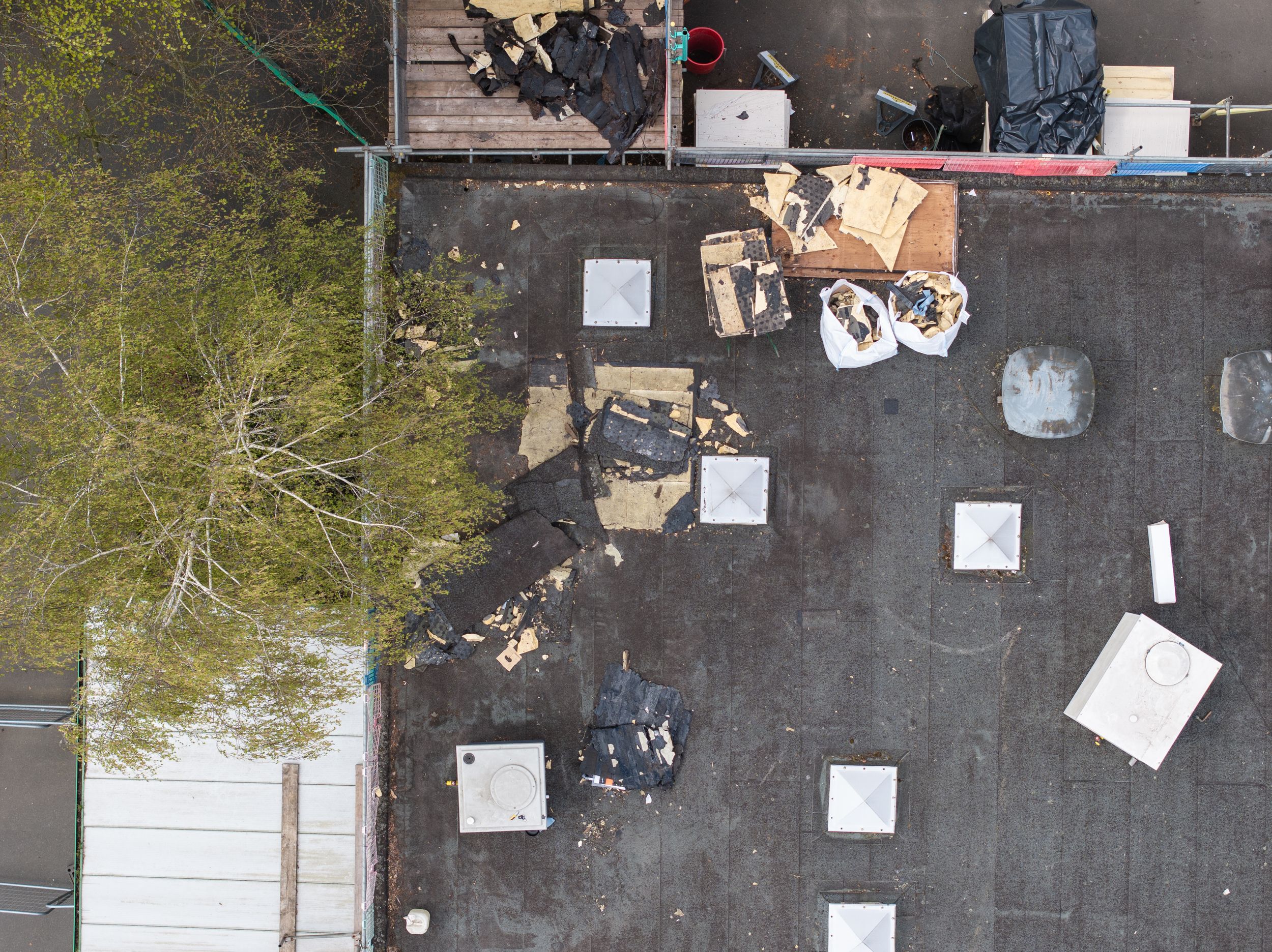 Aerial view of a rooftop with scattered debris and square white panels arranged in a grid pattern.
