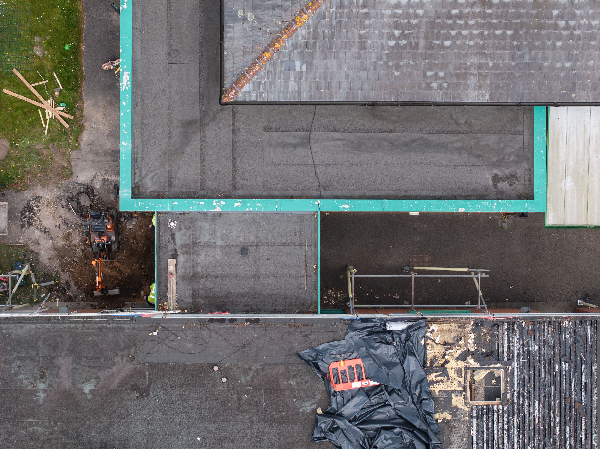 Aerial view of a building corner showing gray roofing and turquoise trim details.