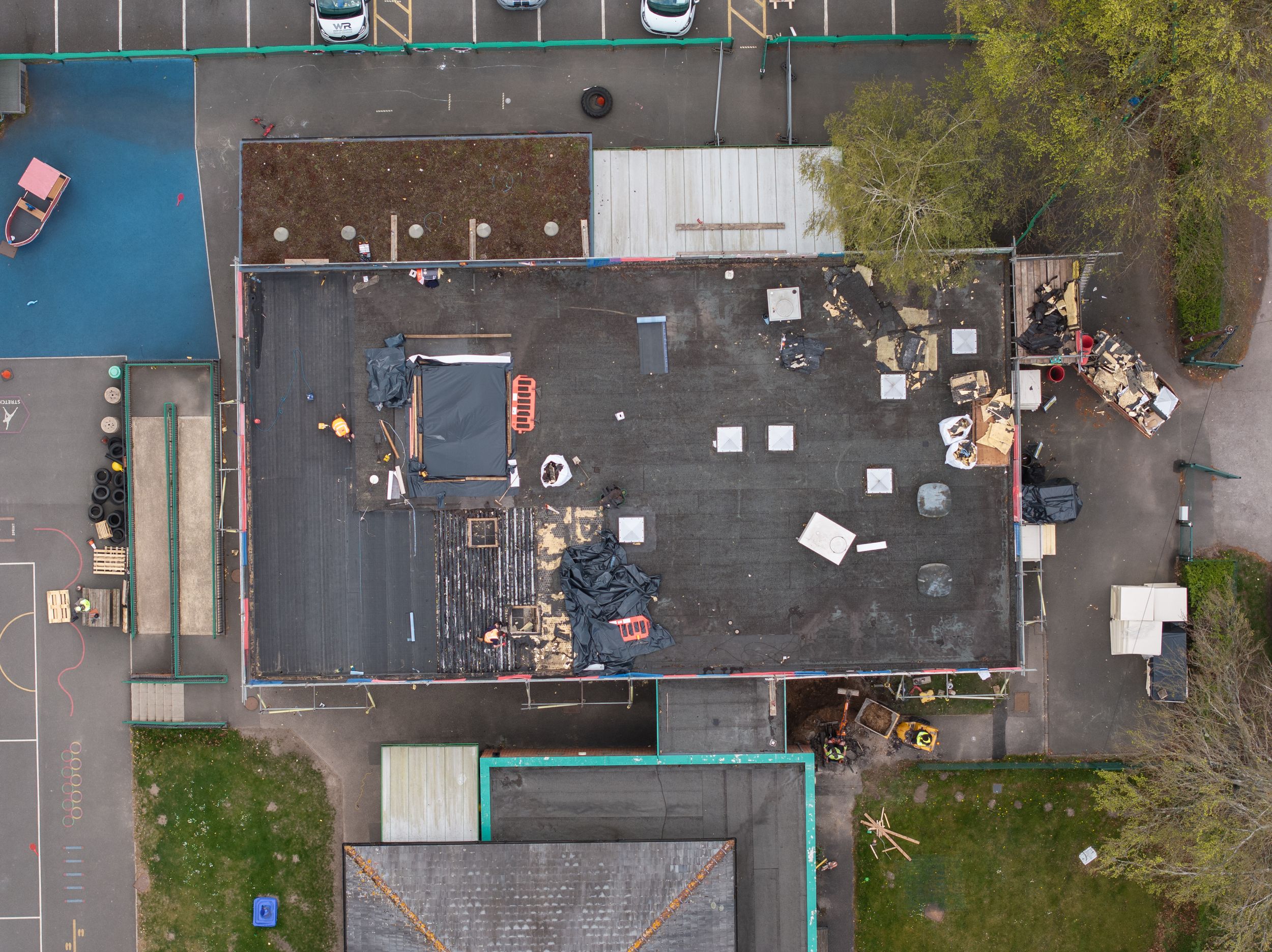 Bird's eye view of a building rooftop covered in scattered equipment and materials.