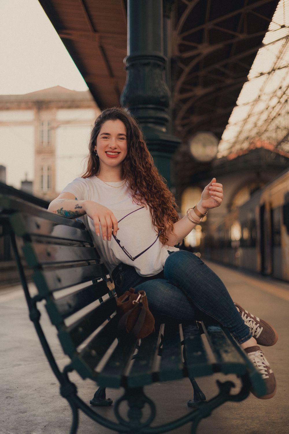 Casual portrait on vintage bench at train station platform with golden hour lighting.