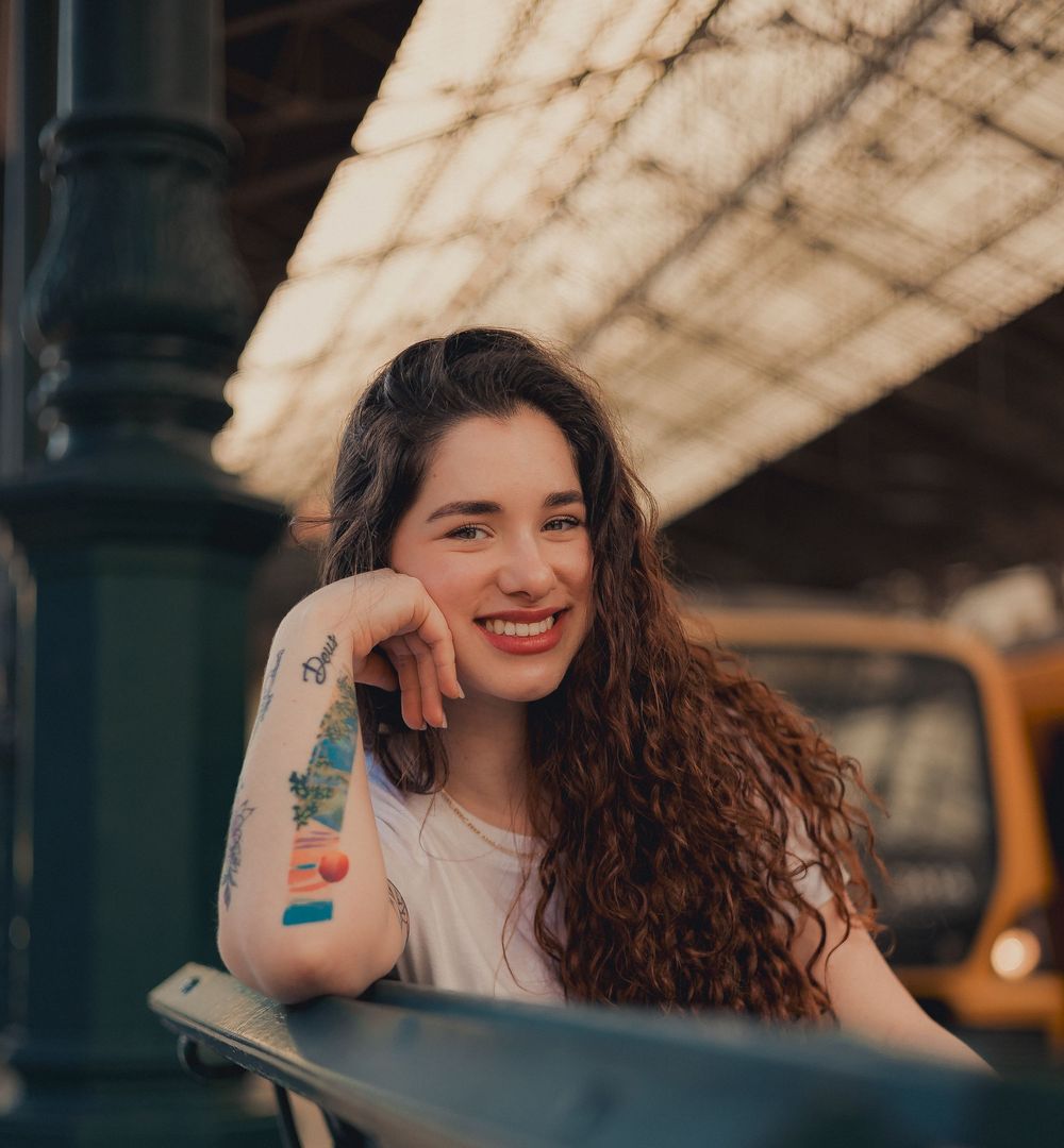 Candid portrait showcasing colorful arm tattoos and natural curls.