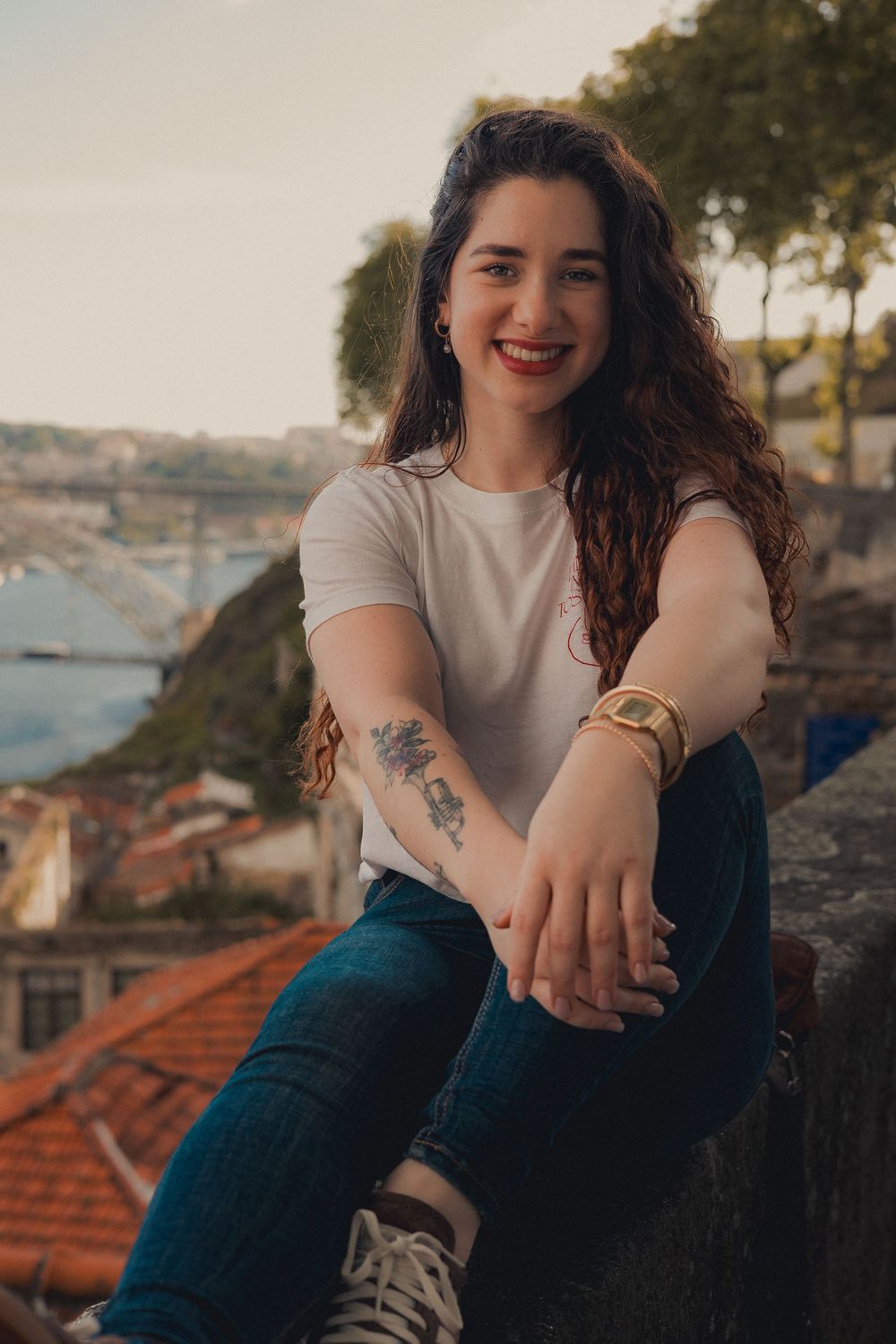 Casual outdoor portrait with city rooftops and river view in Porto, Portugal.