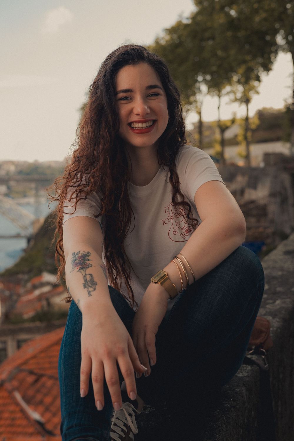 Candid outdoor portrait with city view and visible tattoo artwork.