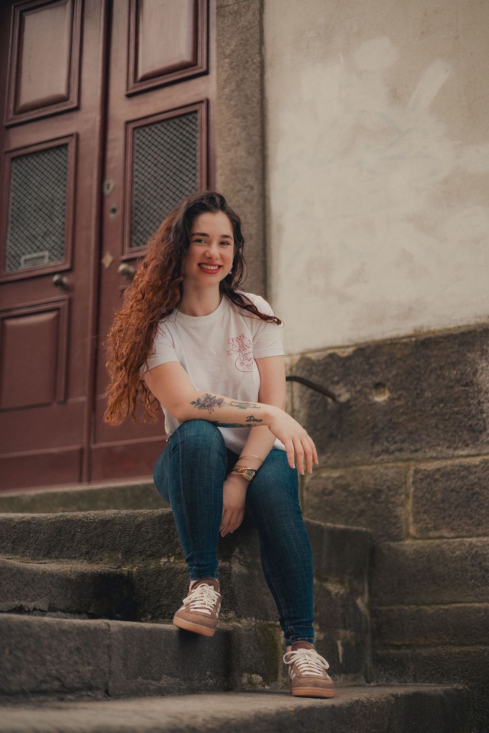 Casual portrait sitting on stone steps near vintage wooden door.