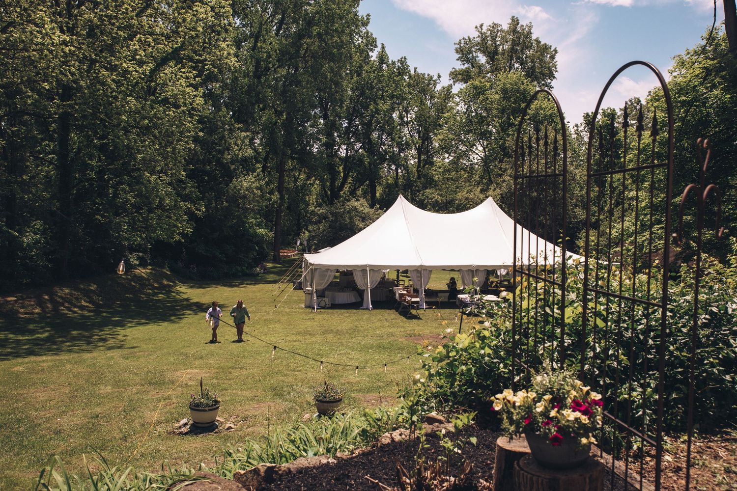 Panoramic view of an outdoor wedding venue with white tent and natural landscaping.