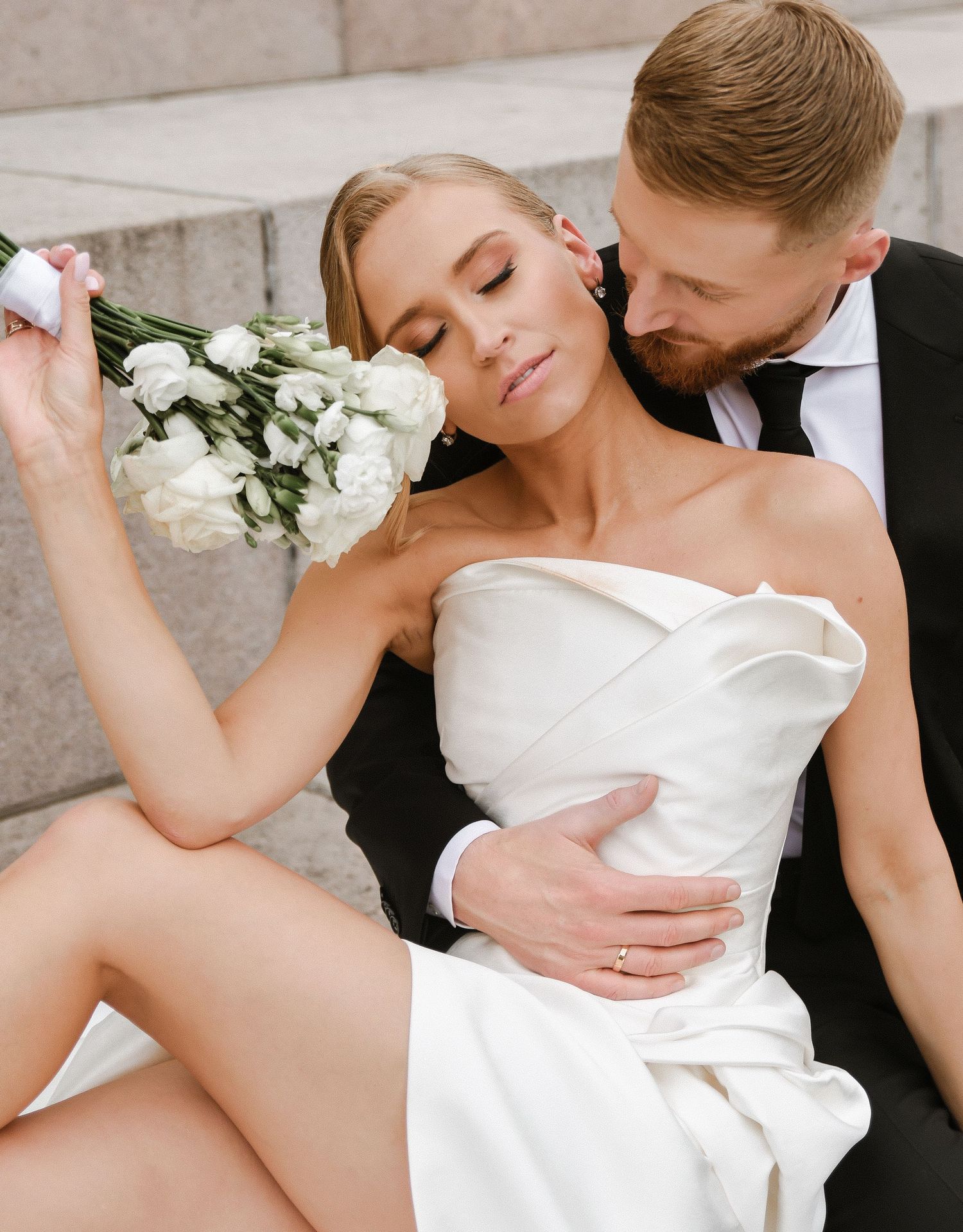 A couple dances together in formal wedding attire on a city street as they celebrate their marriage.