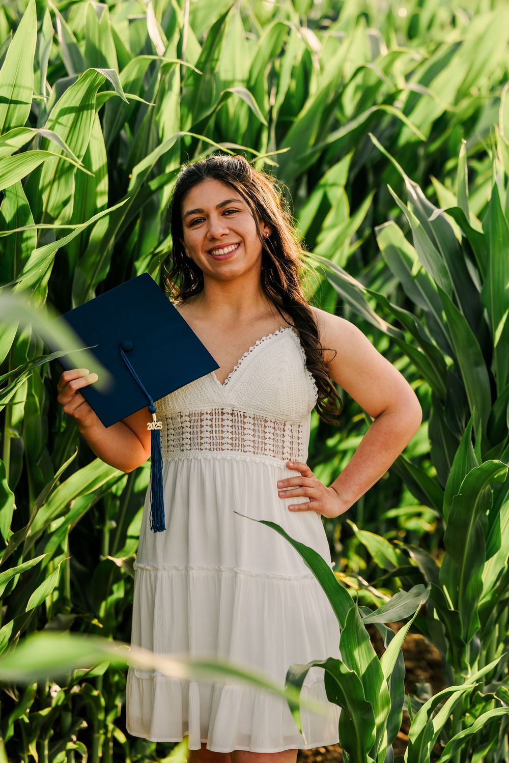 A summer photo shoot in a lush green cornfield wearing a white sundress with crochet details.